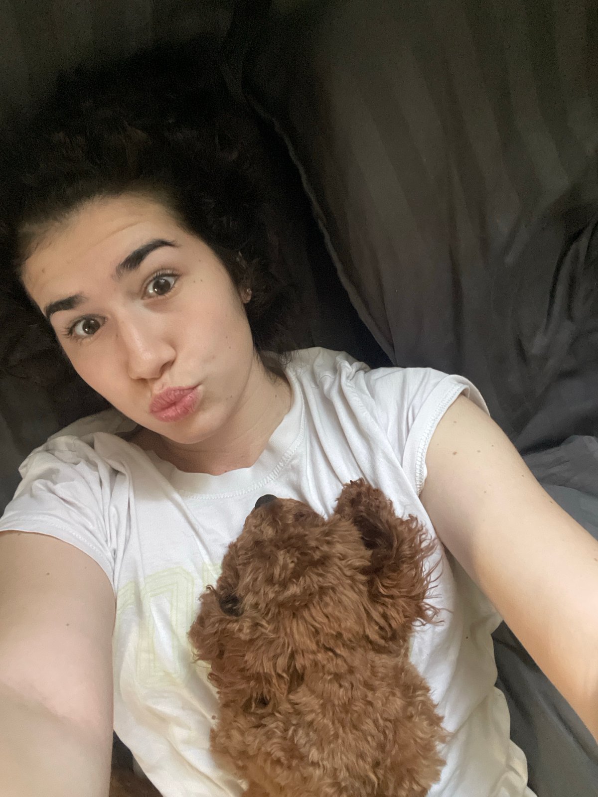 Woman shares morning bed time with small brown dog