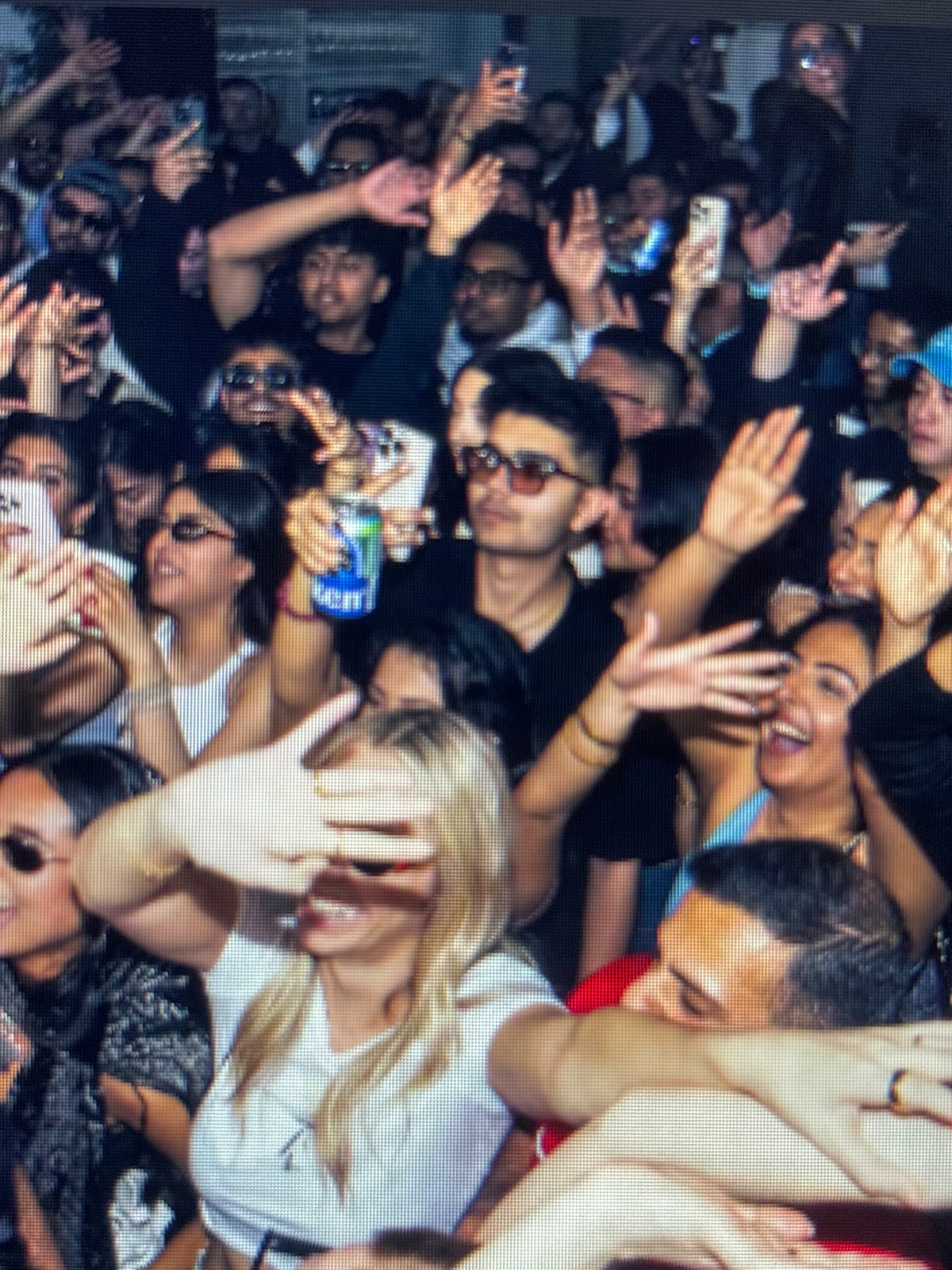 Packed indoor venue, geometric light rig, crowd at full energy
