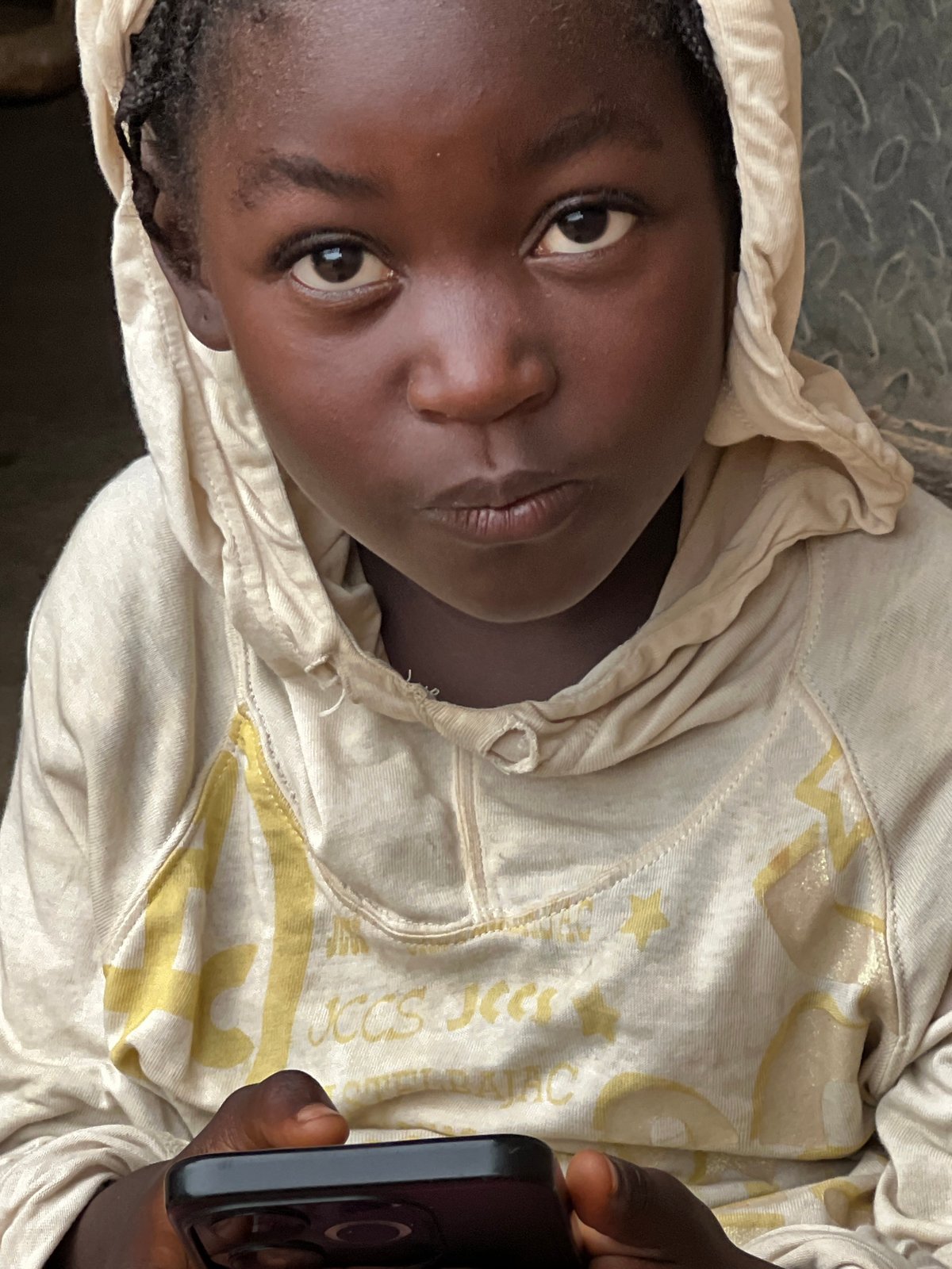 Scrolling through a phone near a metal wall in Jos