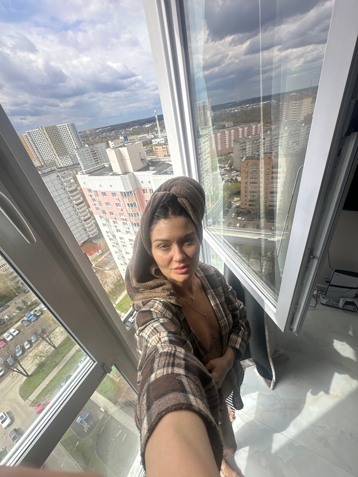 Woman in towel and robe observed near window in Moscow