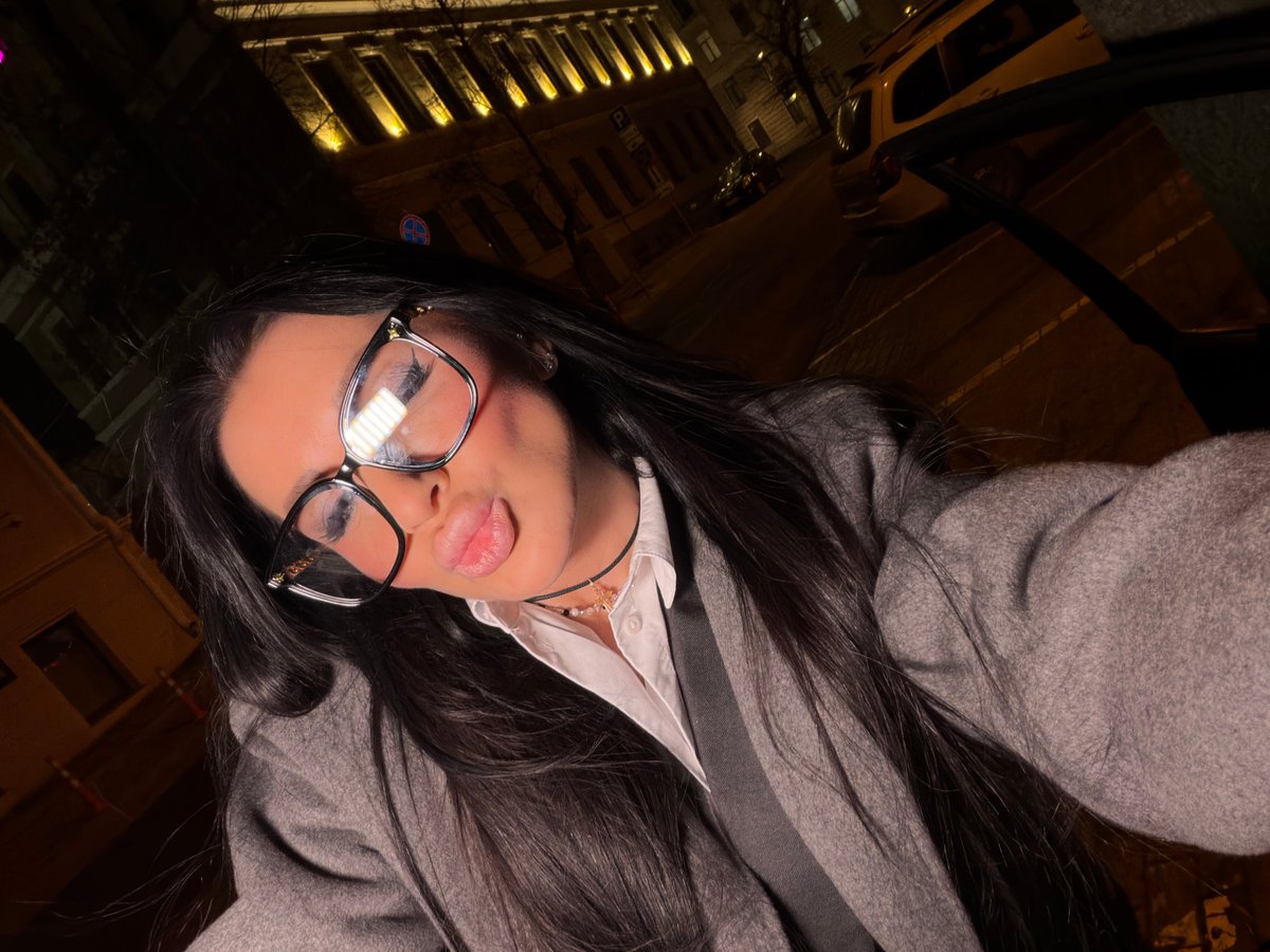 Woman takes nighttime selfie near illuminated building in Voronezh
