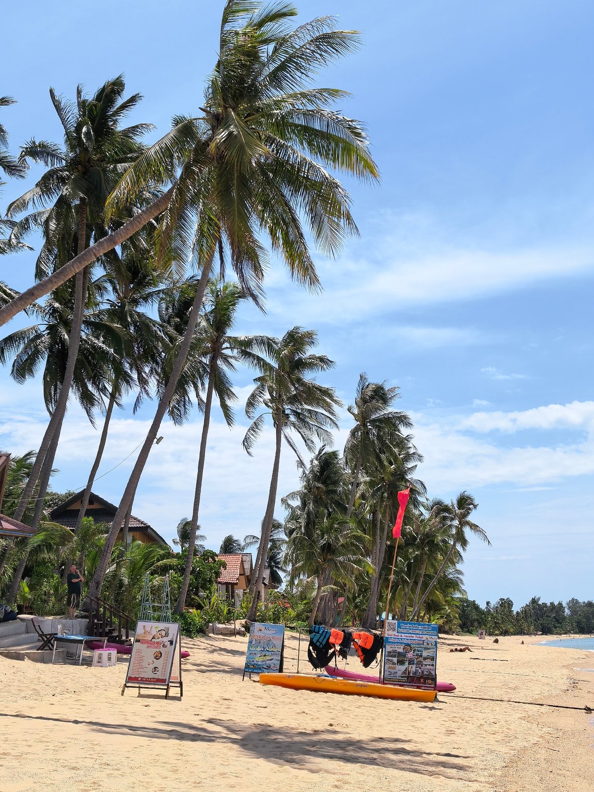 Busy Ko Samui beach morning with boats, jet skis, and fruit stands