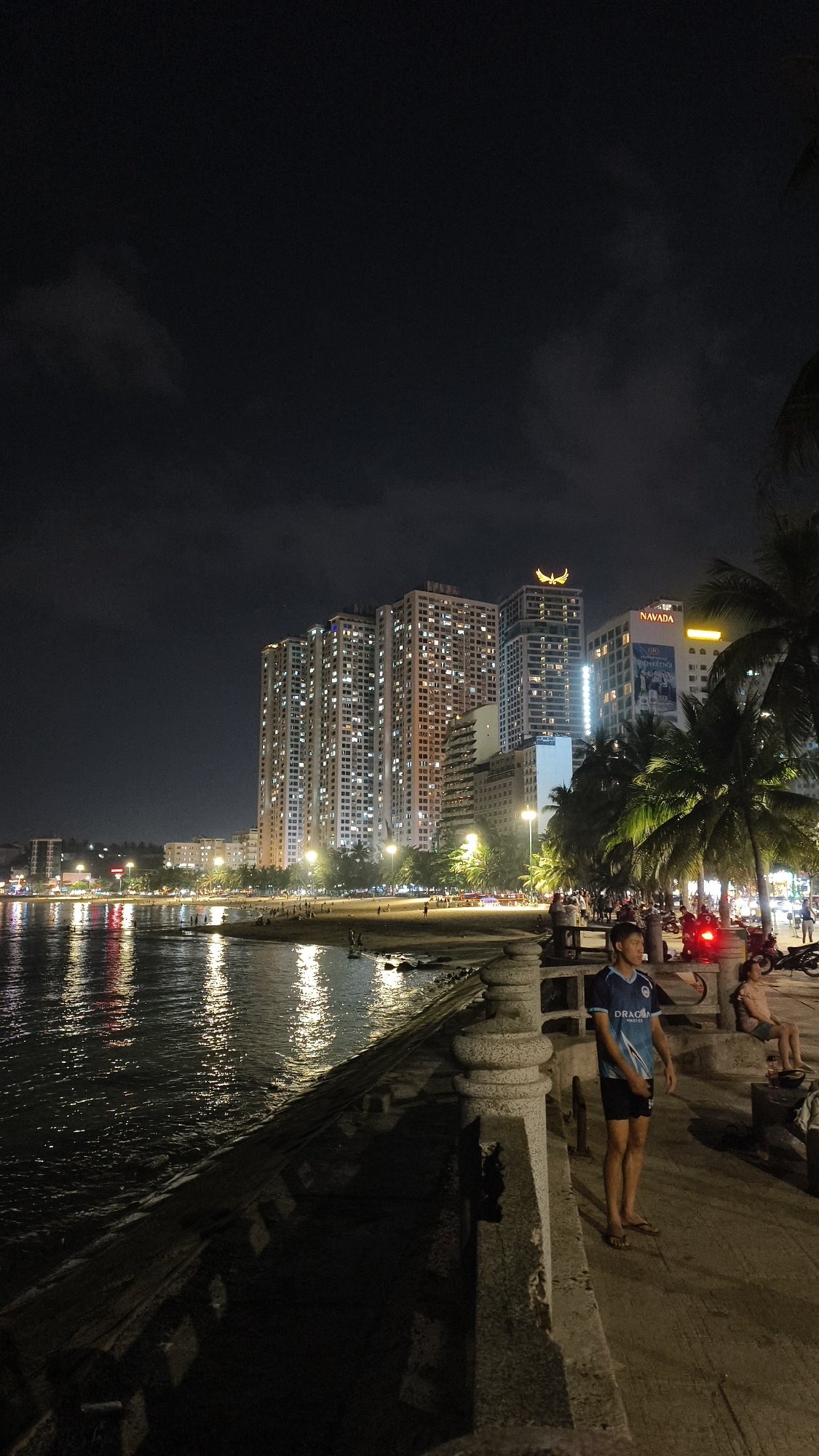 Nighttime beach promenade and lantern-lit tree with parked motorcycles