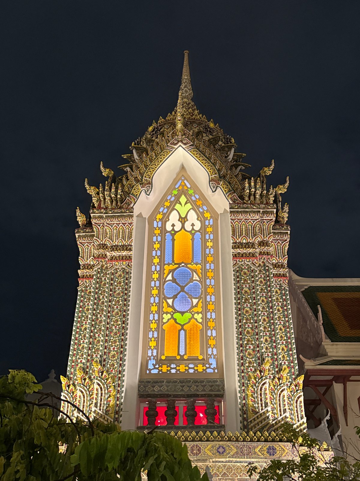 Bangkok temple facade glows at night, stained glass on display
