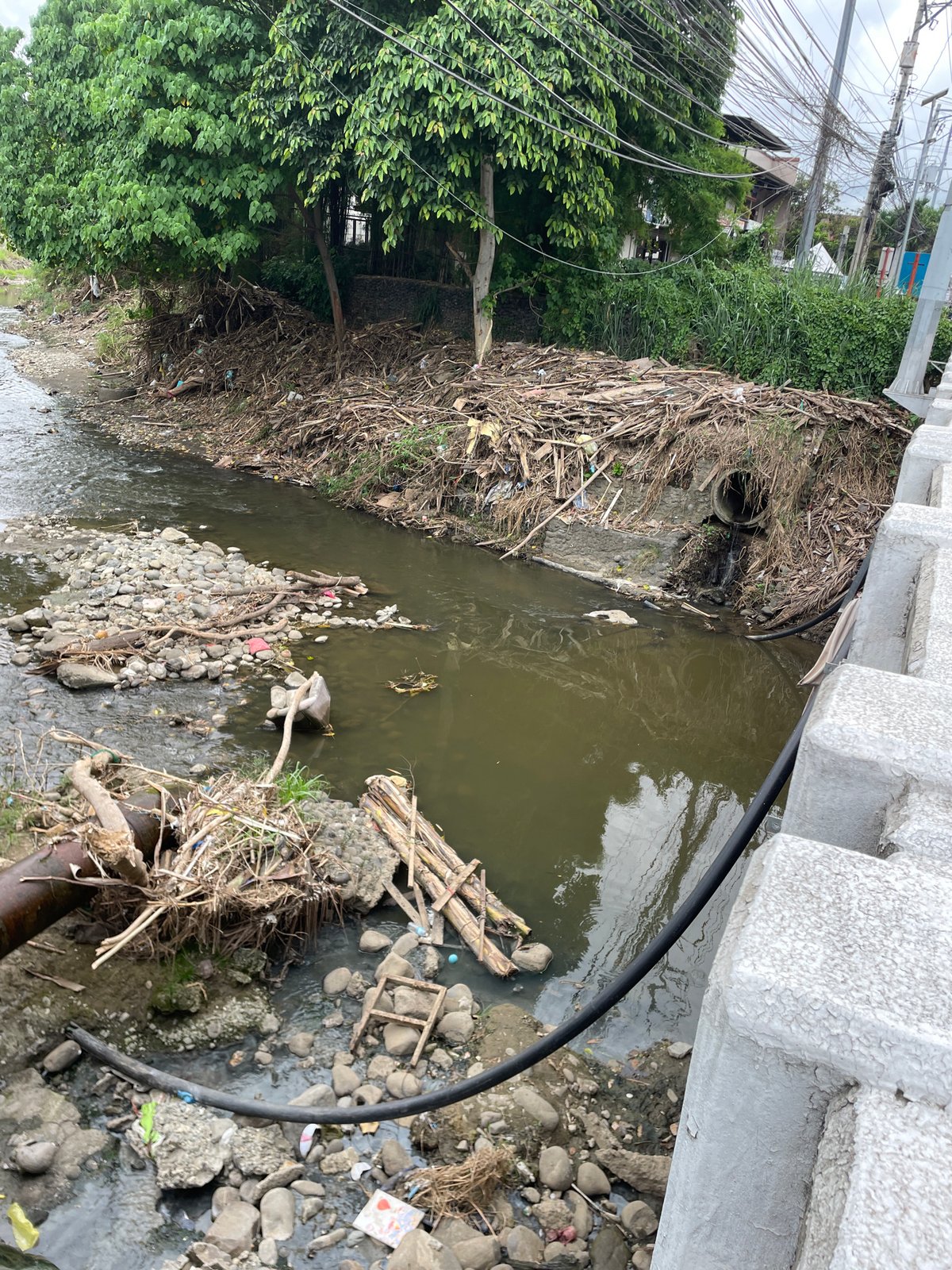 Polluted riverbank documented in Davao City amid normal traffic