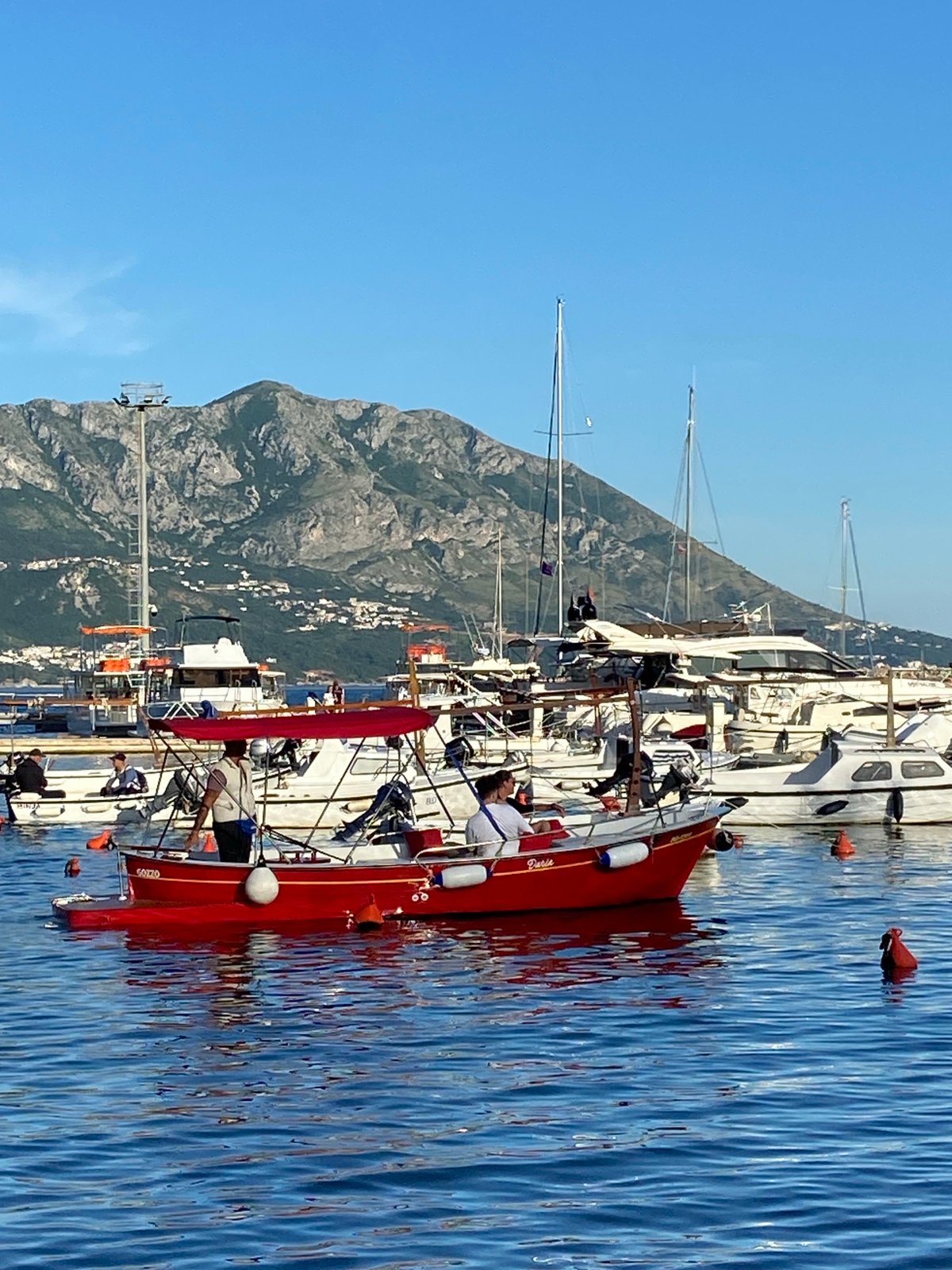 Budva waterfront activity captured with yachts, passenger boat, local cat