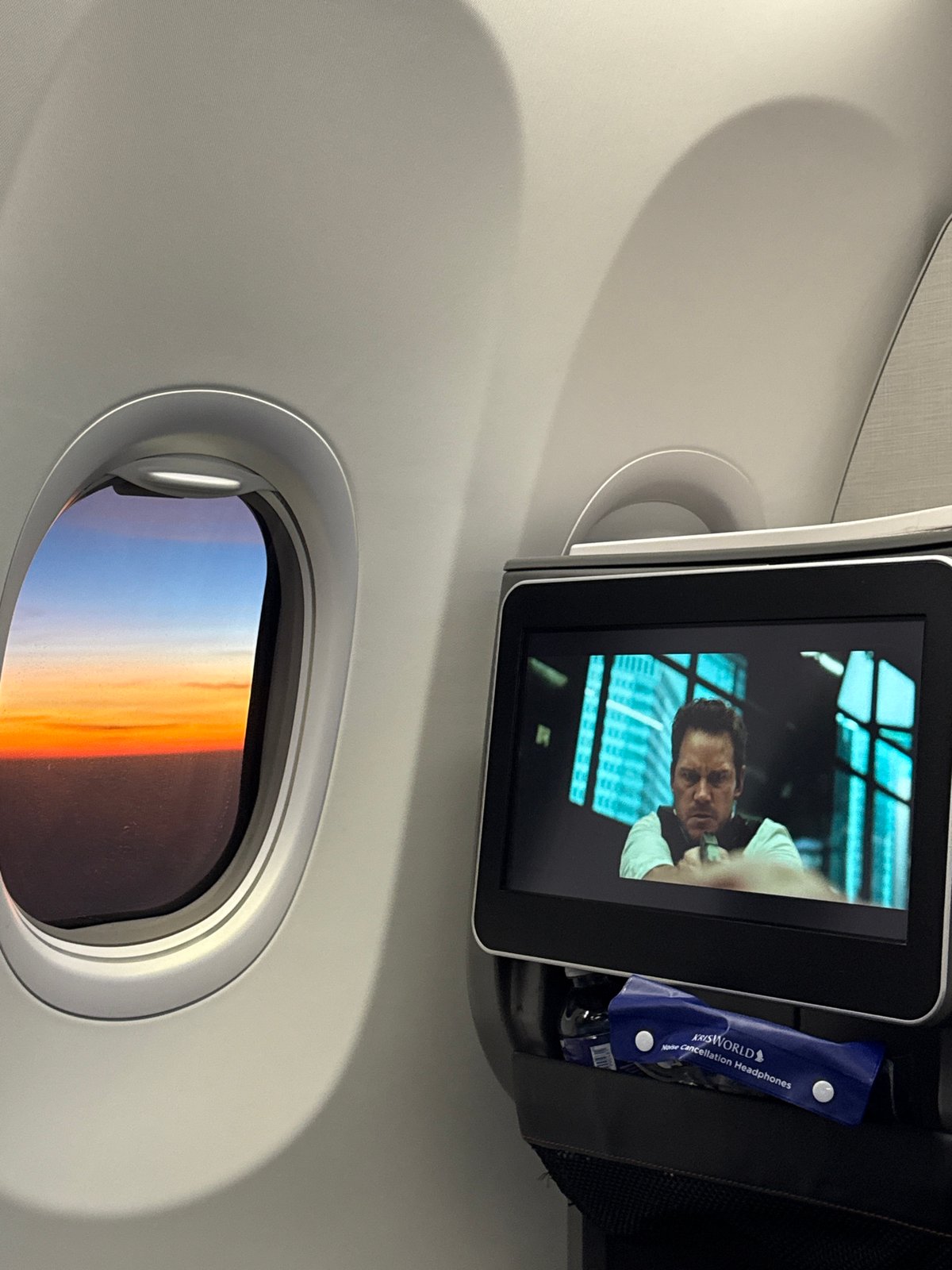 Passenger captures airplane window view with seatback entertainment screen