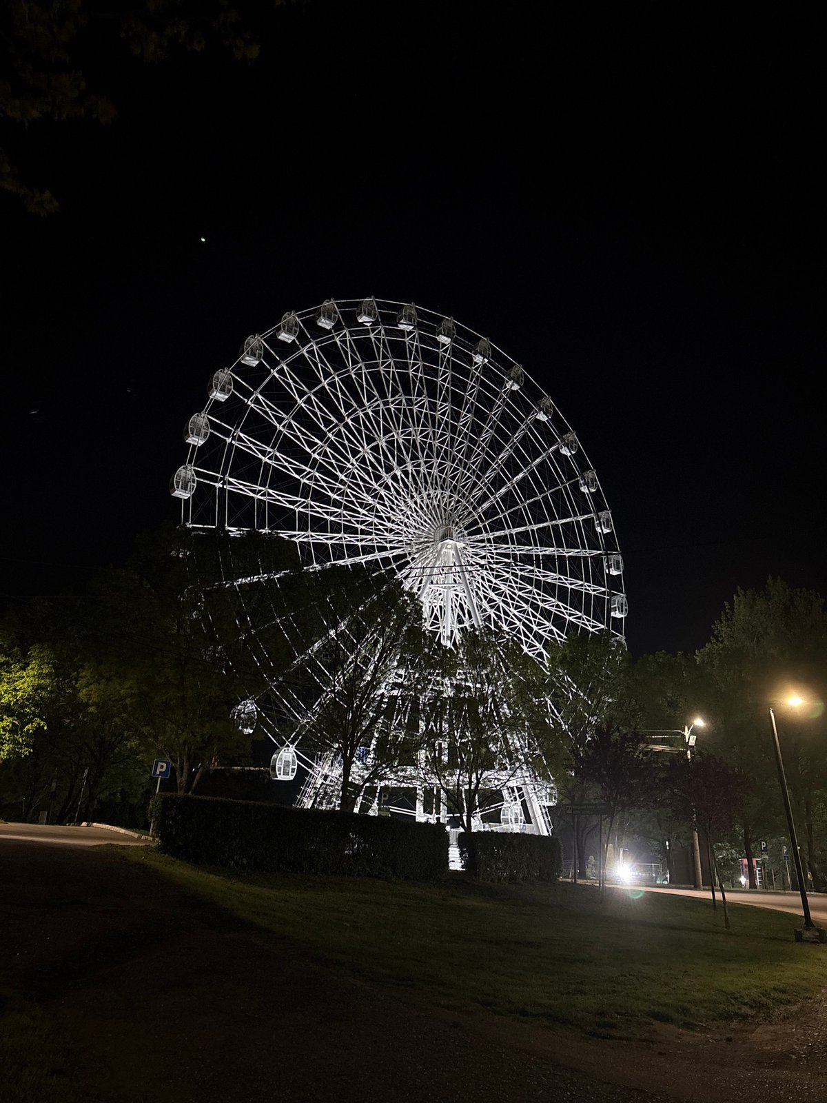 Illuminated Ferris wheel operates at night in Serbian municipality