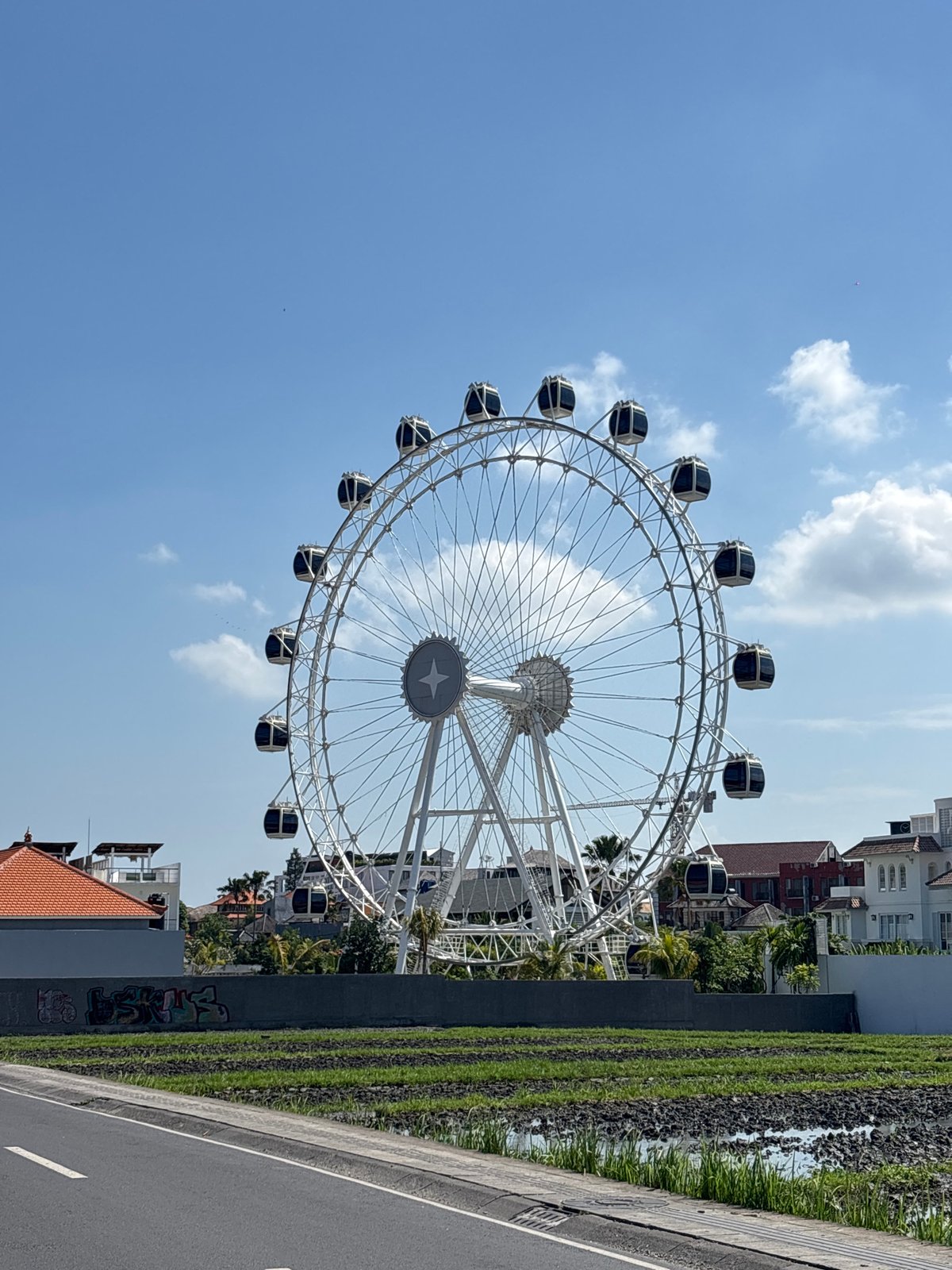 Ferris wheel rises above rice paddies in North Kuta, Bali