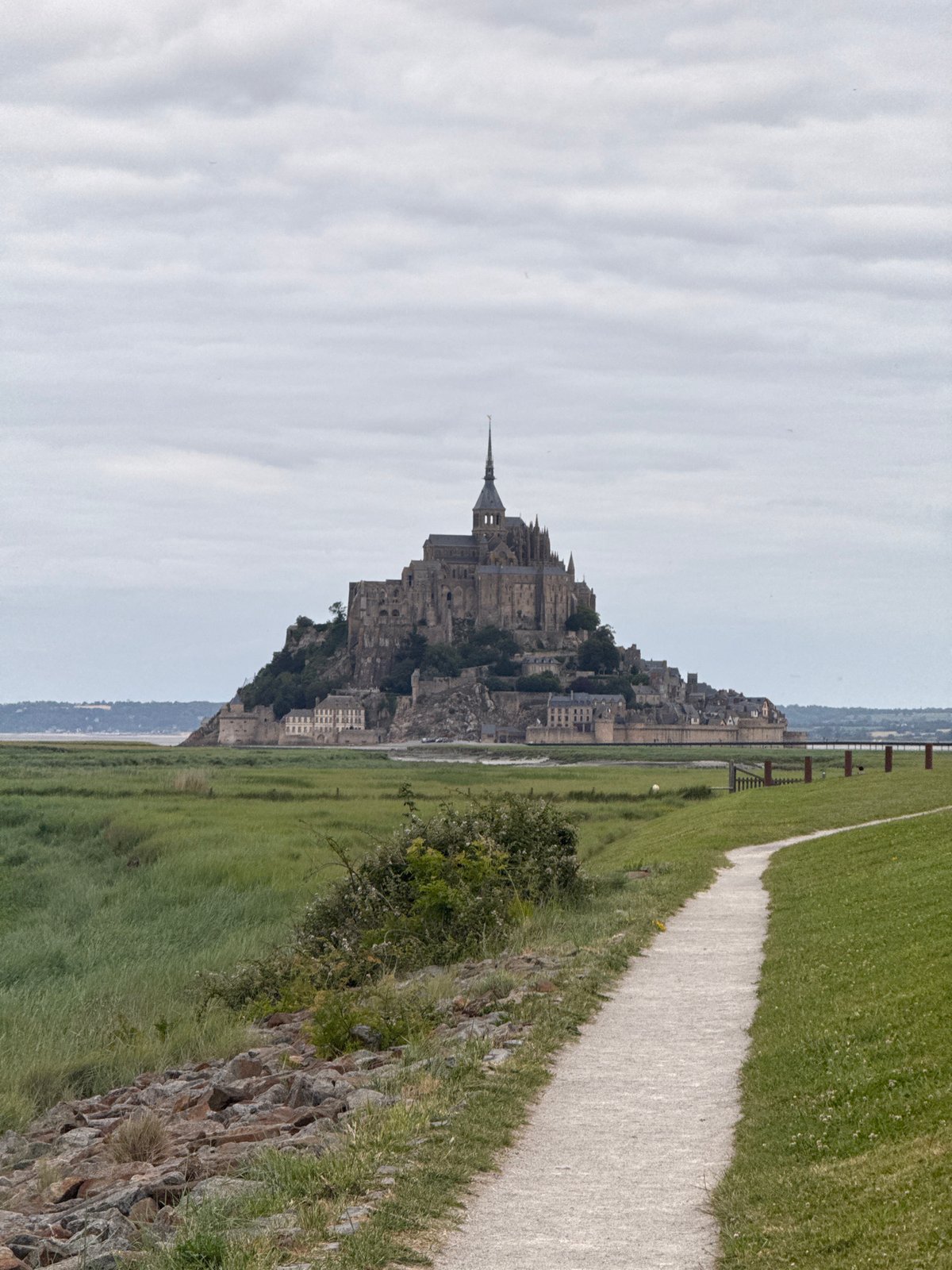 Visitor documents Mont Saint-Michel abbey under overcast skies