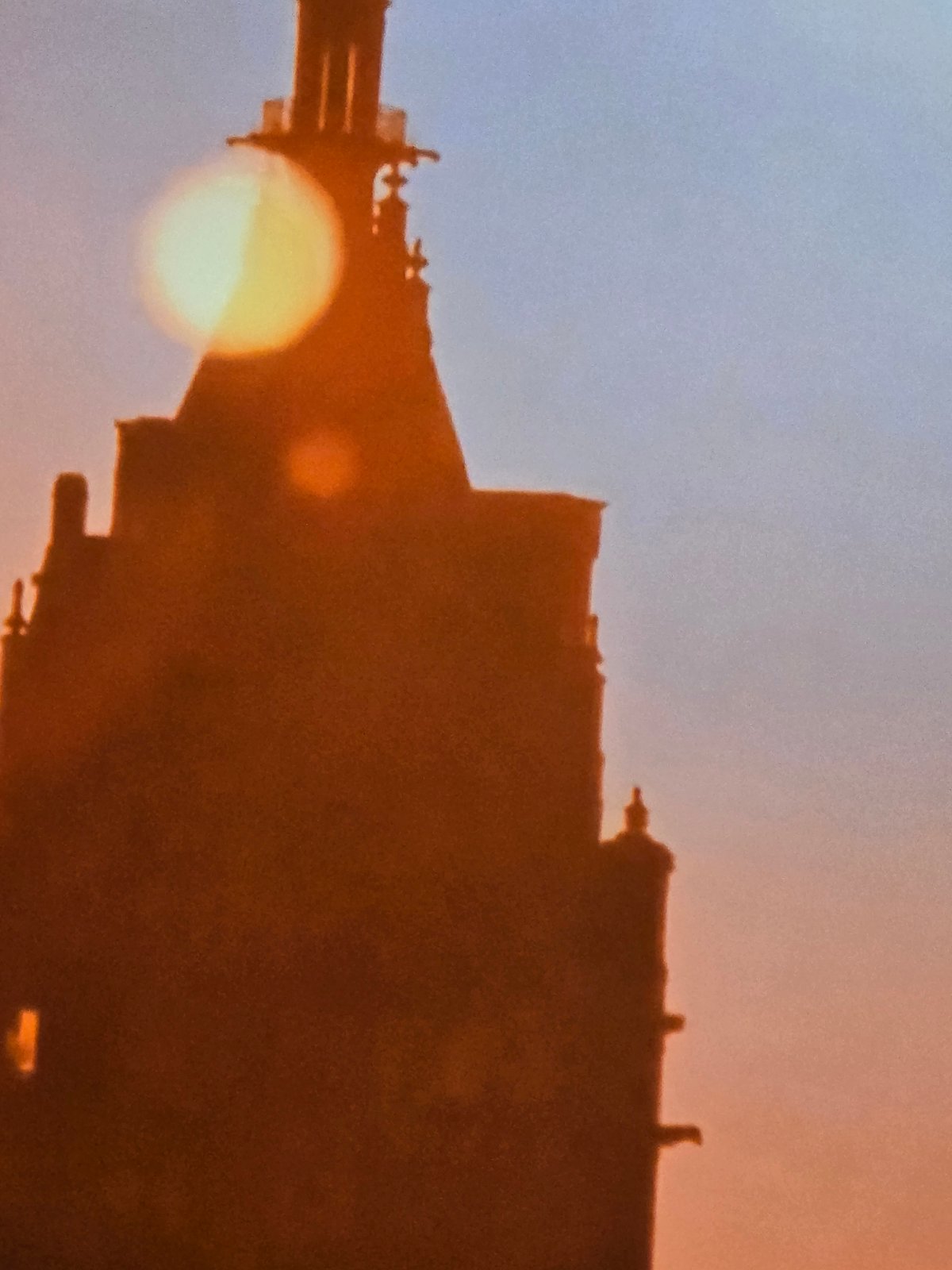 Building silhouetted against sunset sky with obscured sun