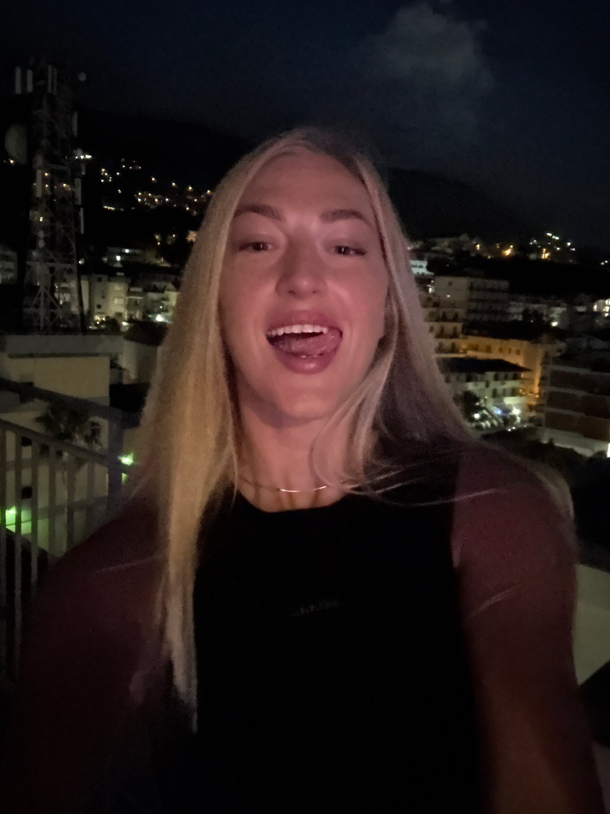 Nighttime outdoor selfie in a black top and gold necklace.