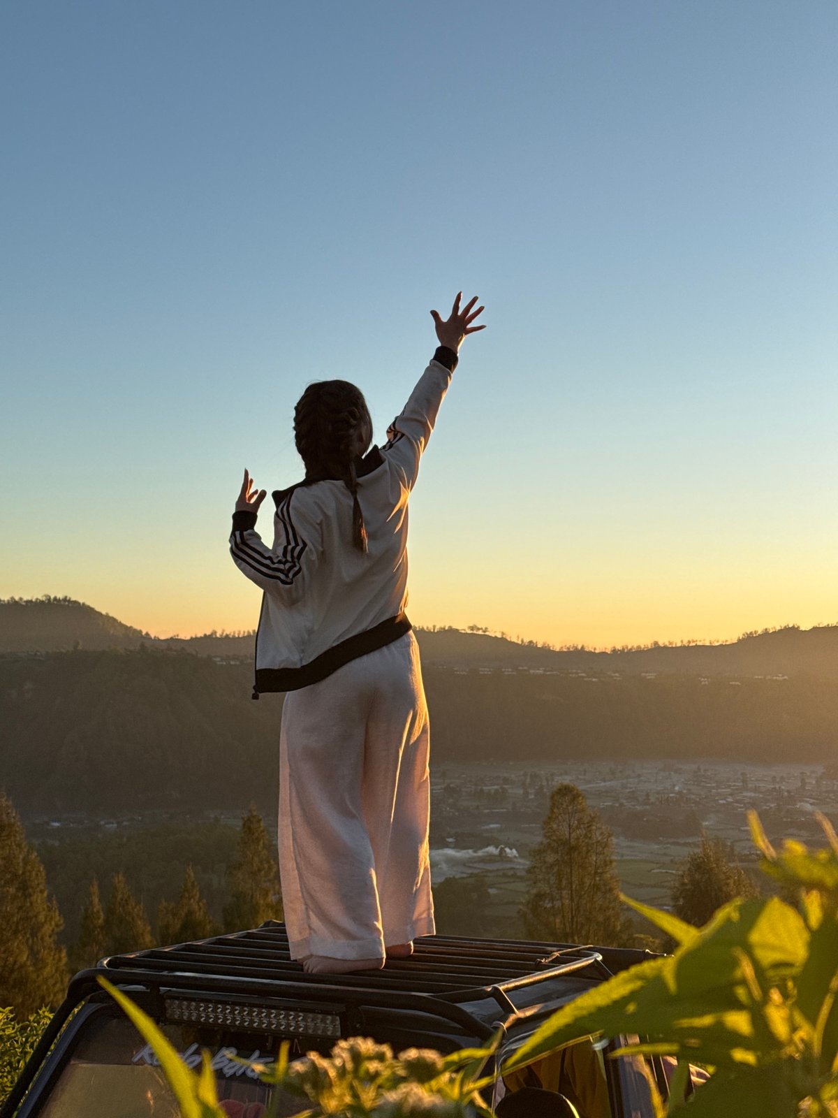 Arms raised at sunrise above Kintamani's volcanic highland views