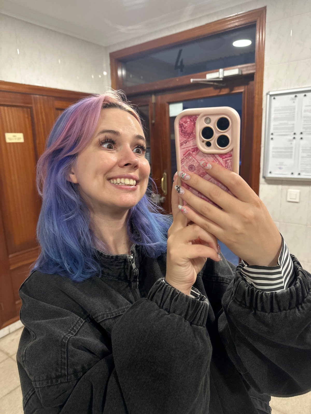 Woman with rainbow hair takes selfies in Gijón elevator