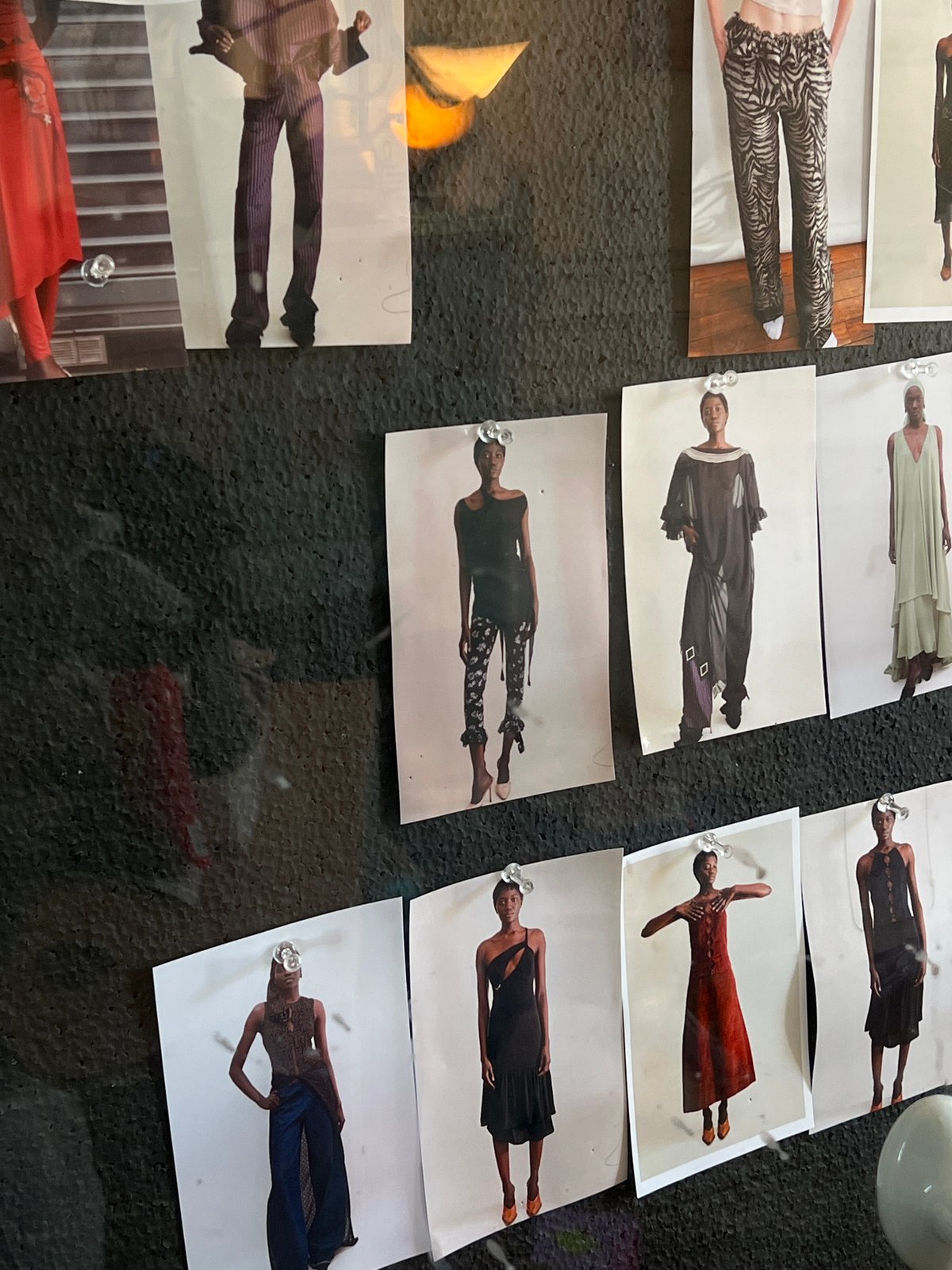 Fashion photos displayed on bulletin board at unknown location