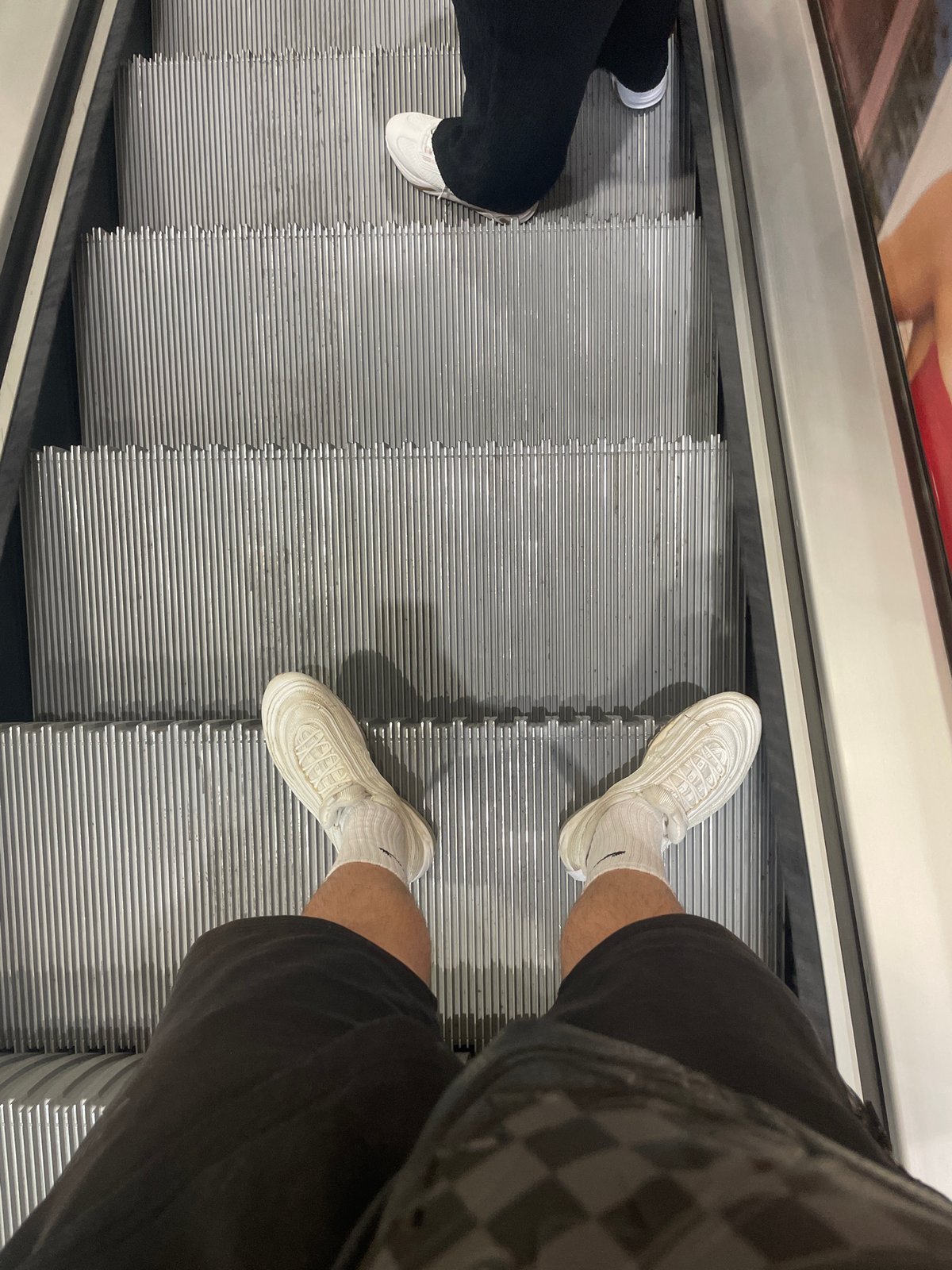 Two people ride escalator in Sofia wearing casual footwear
