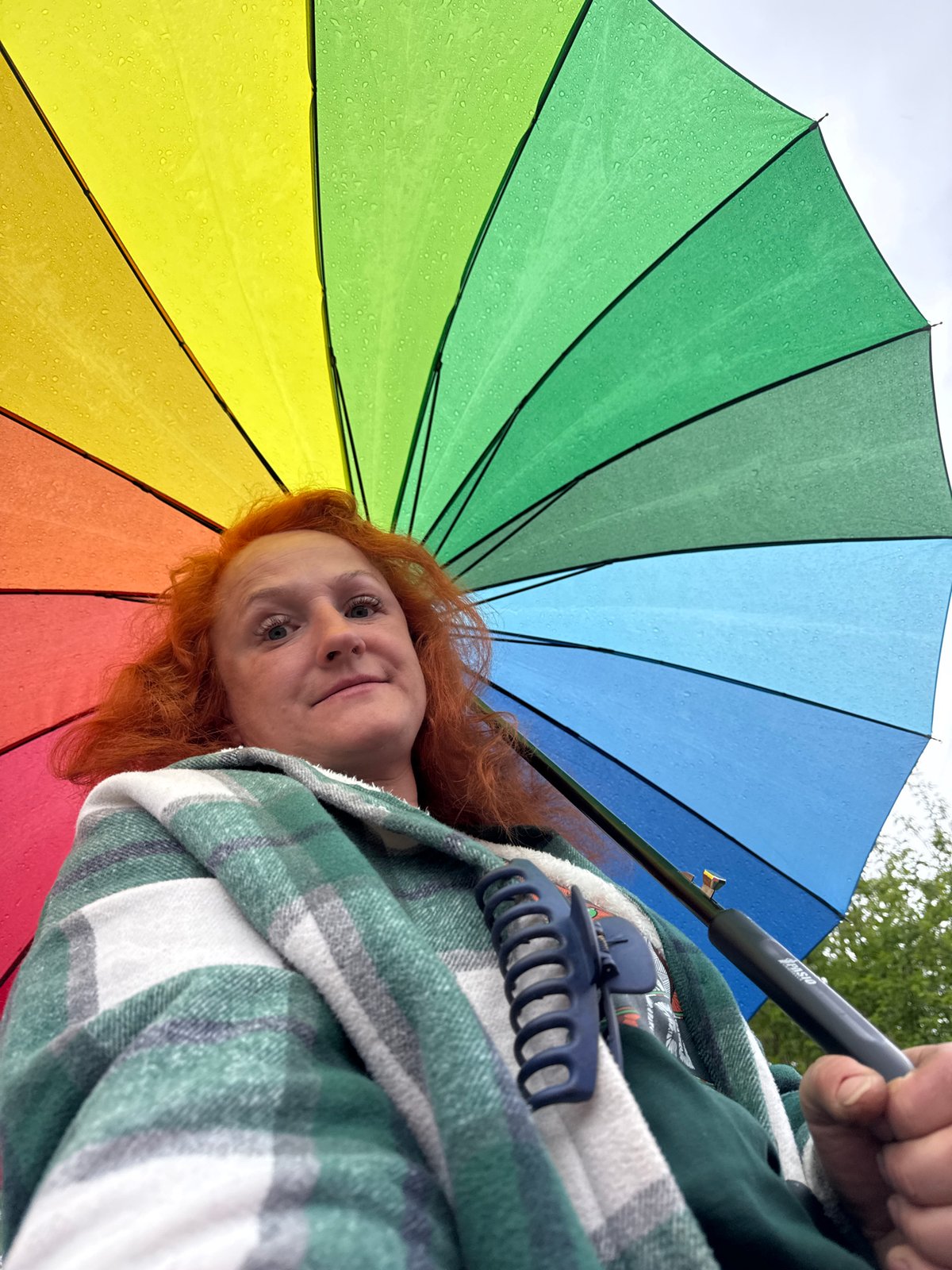 Woman with rainbow umbrella walks through rainy Chaikovsky morning
