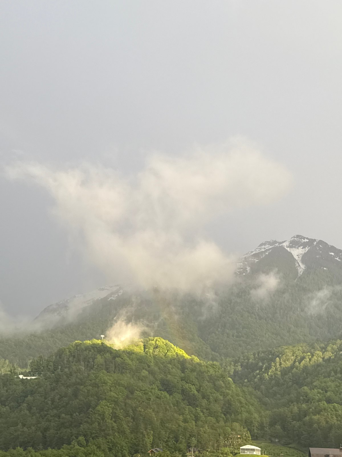 Rainbow appears through misty mountain weather in Krasnaya Polyana