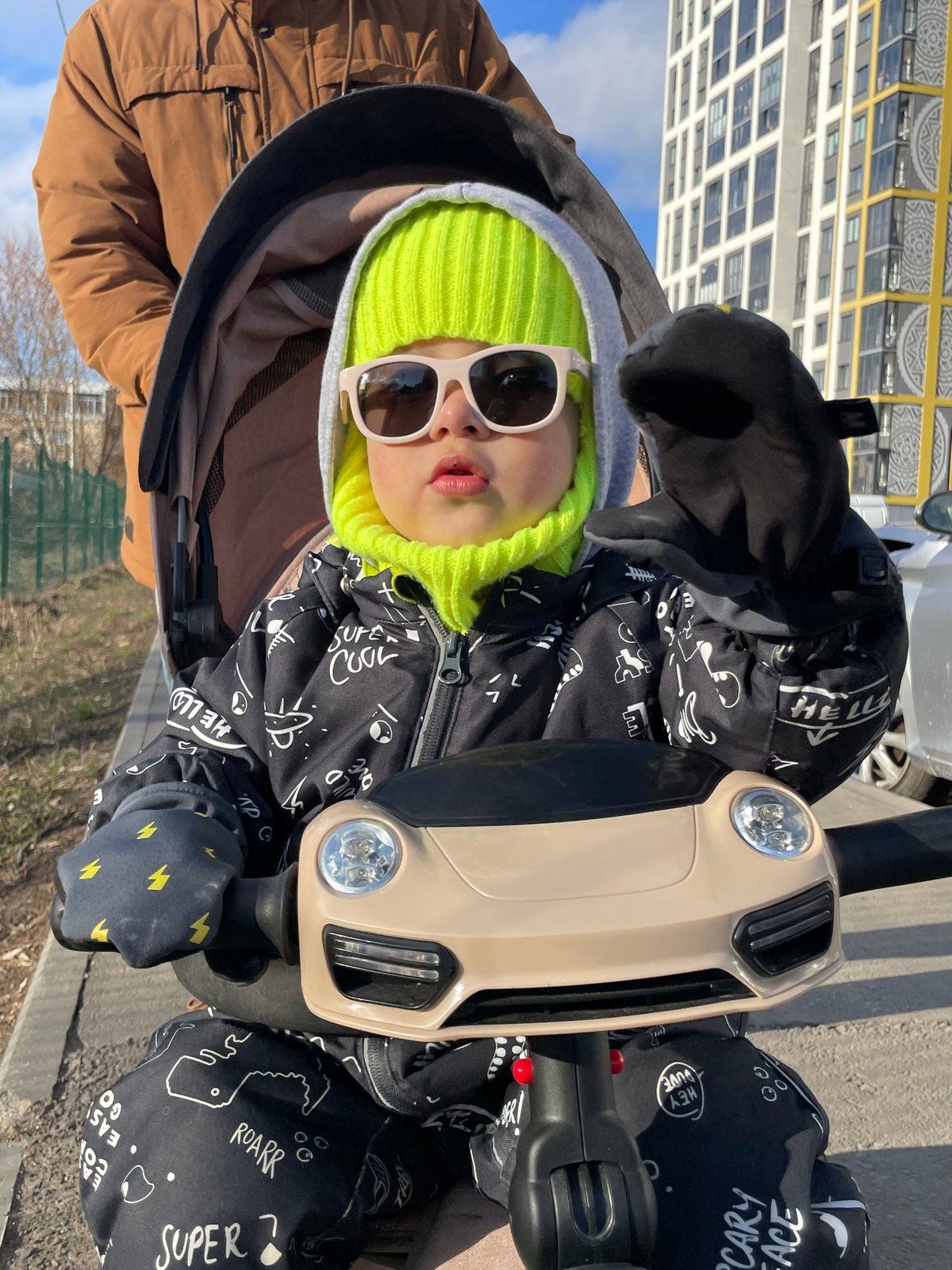 Child enjoys ride-on toy outdoors in sunny Izhevsk