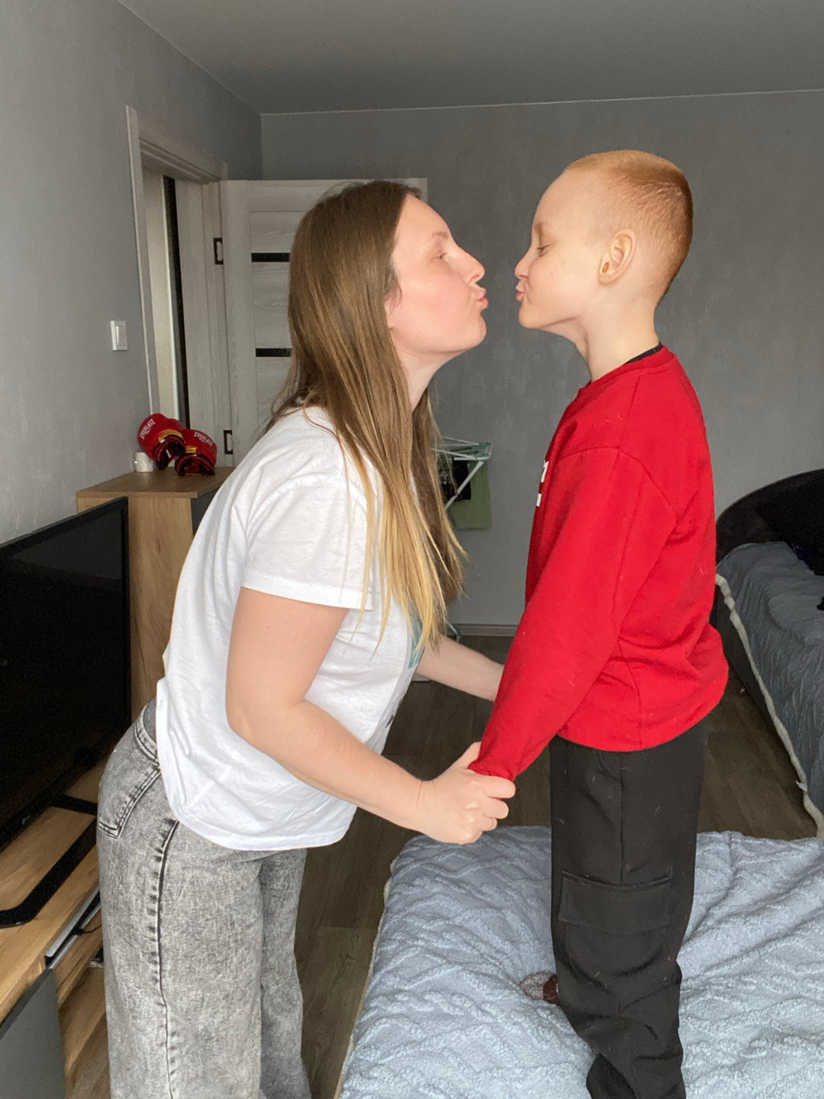 Woman lifts young boy indoors in Noviy, Russia