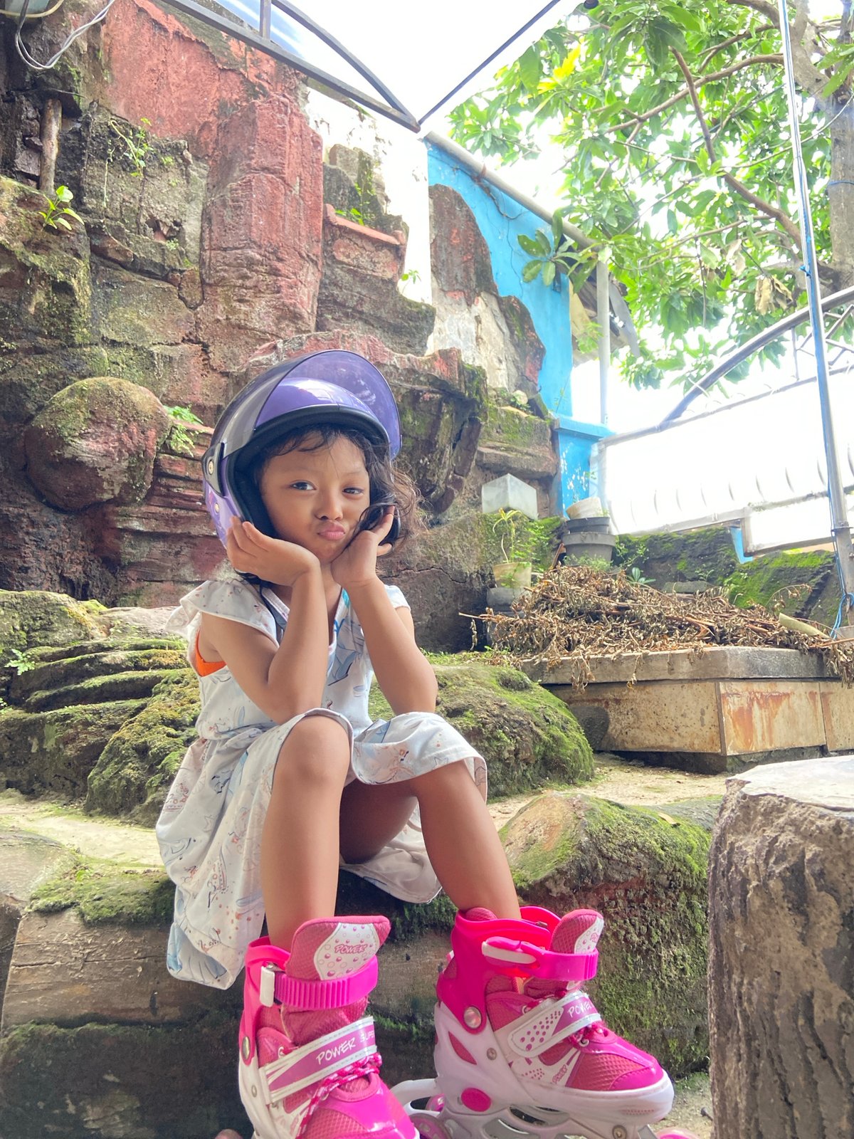 Girl in straw hat plays with roller skates in Gelam