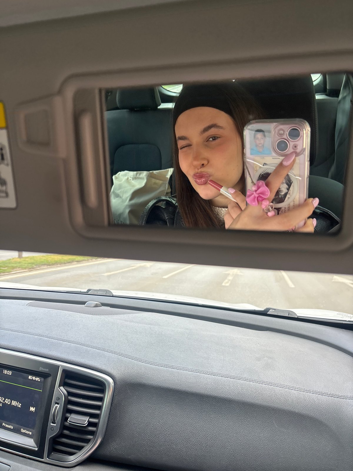 Woman Takes Selfie While Applying Makeup in Car Mirror