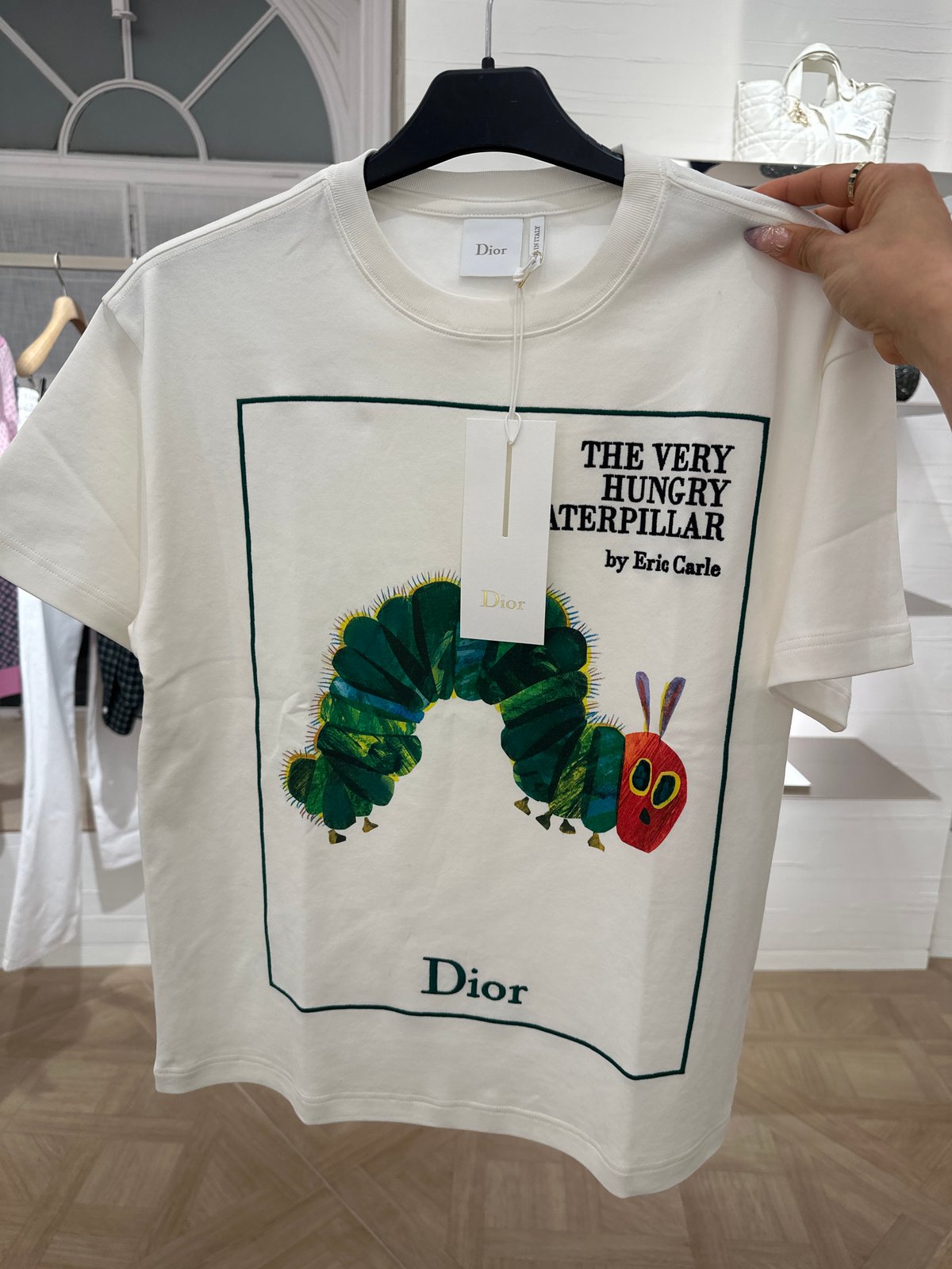 Person examines white graphic t-shirt in London retail store