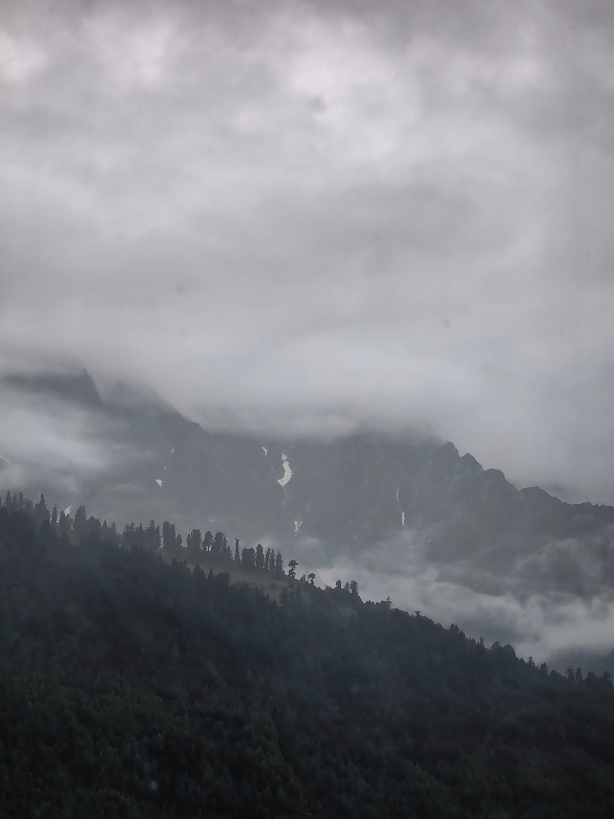 Overcast skies and cloud-draped peaks above Vashisht forests