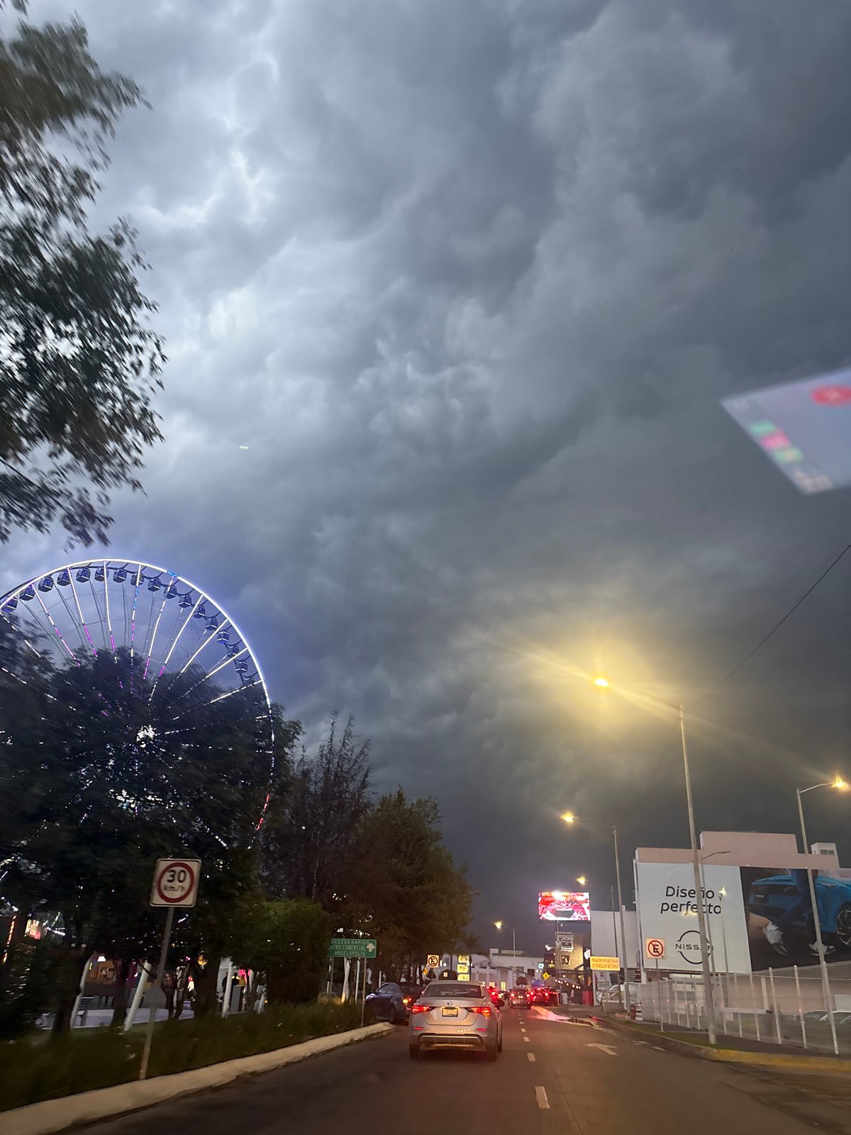 Estrella de Puebla Ferris wheel illuminated purple against cloudy evening