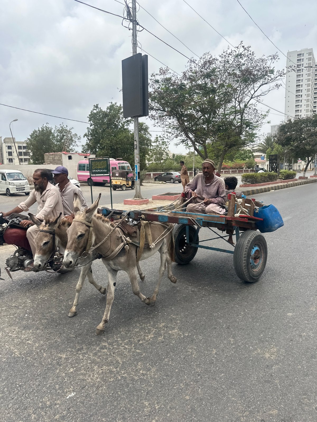 Motorcycle tows a donkey cart through Karachi streets