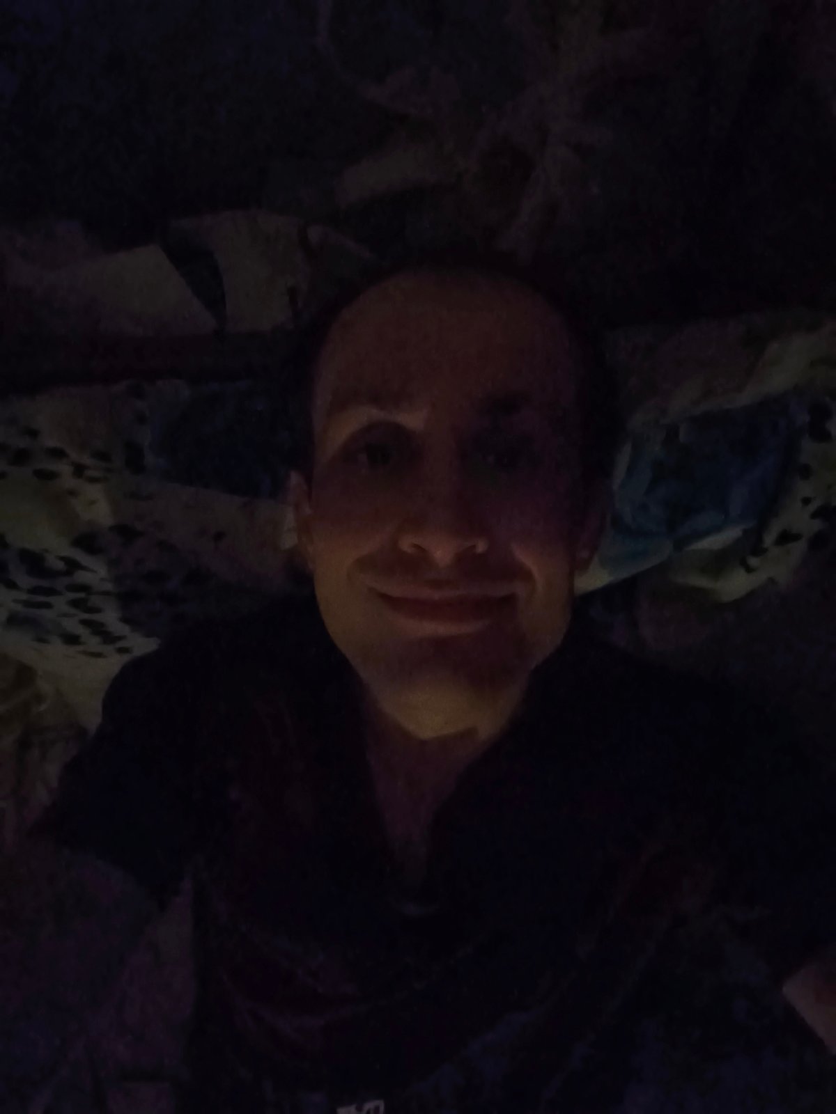 Late-night bedroom selfie session with dim lighting and a tapestry backdrop
