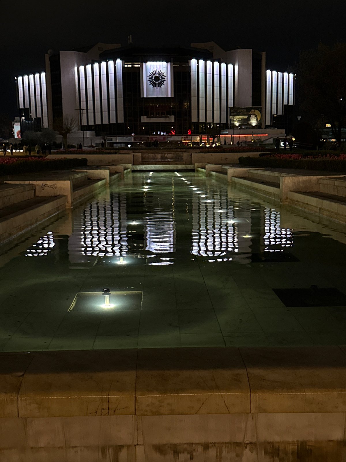 Illuminated modern building reflected in nighttime pool display