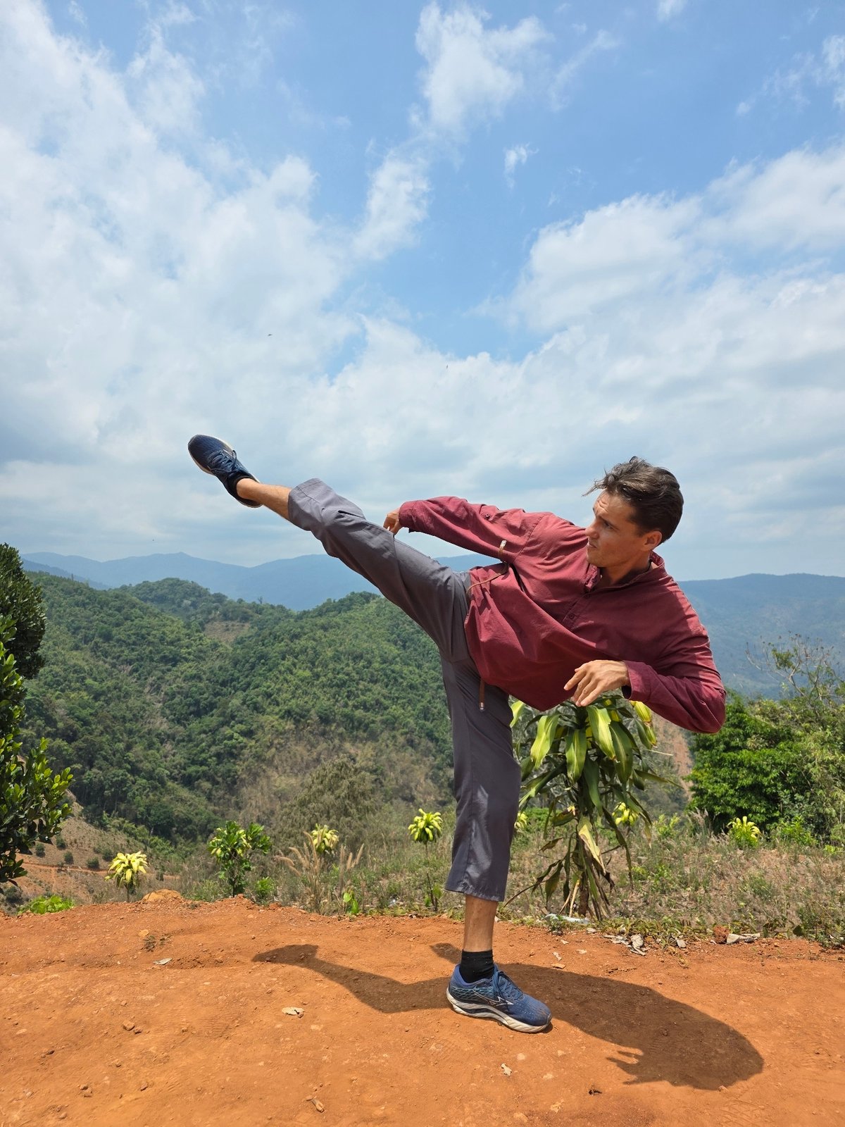 Man performs martial arts kicks on mountain overlook in Vietnam