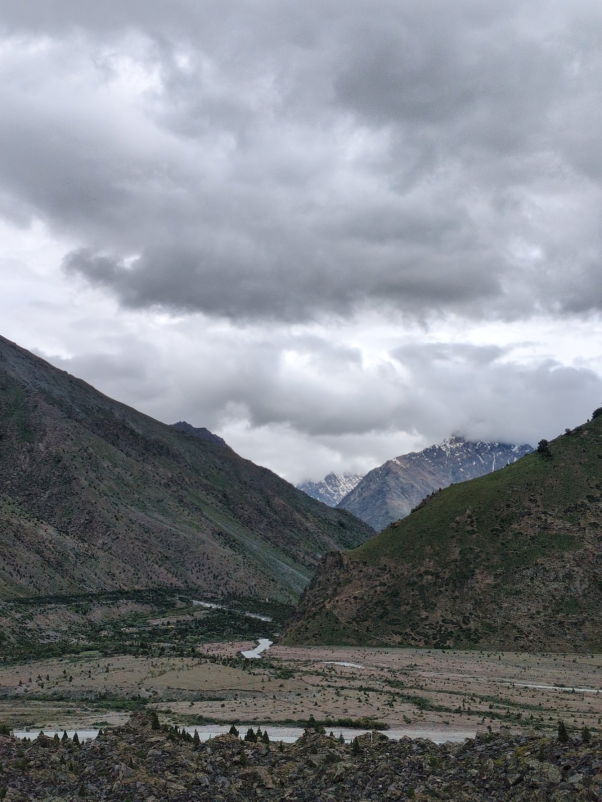 Rocky river valley cuts through overcast mountain terrain in Darcha
