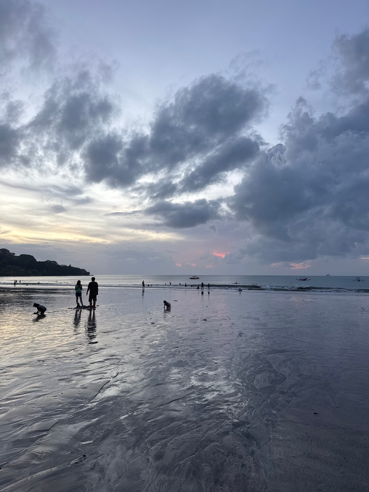 Beach life unfolds during dramatic twilight on coastal shoreline