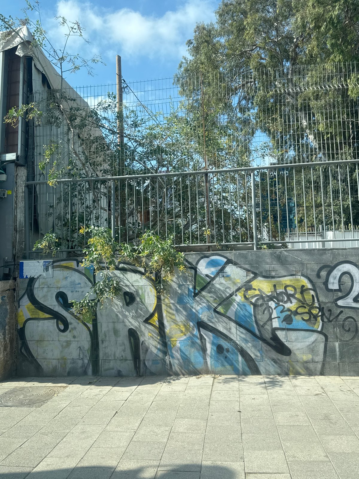 Graffiti wall and shuttered kiosk on a Tel Aviv sidewalk