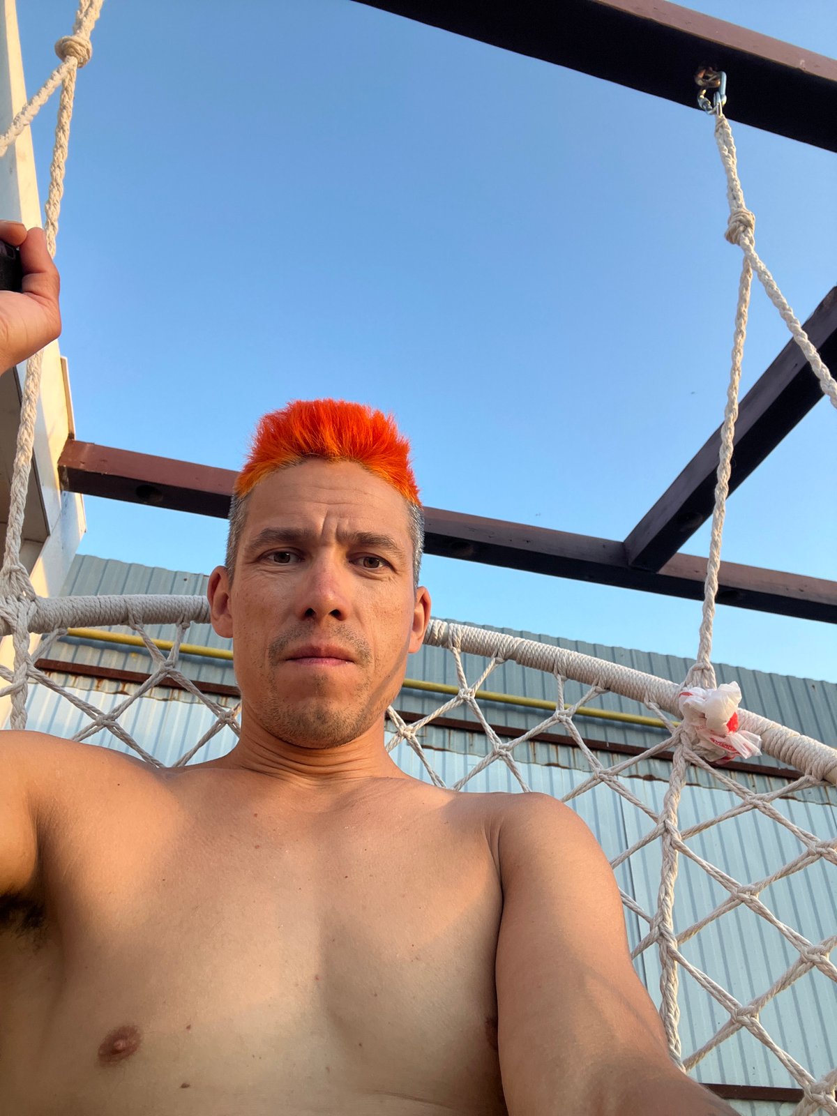 Man tends garden, greenhouse in Chaikovsky during sunset hours