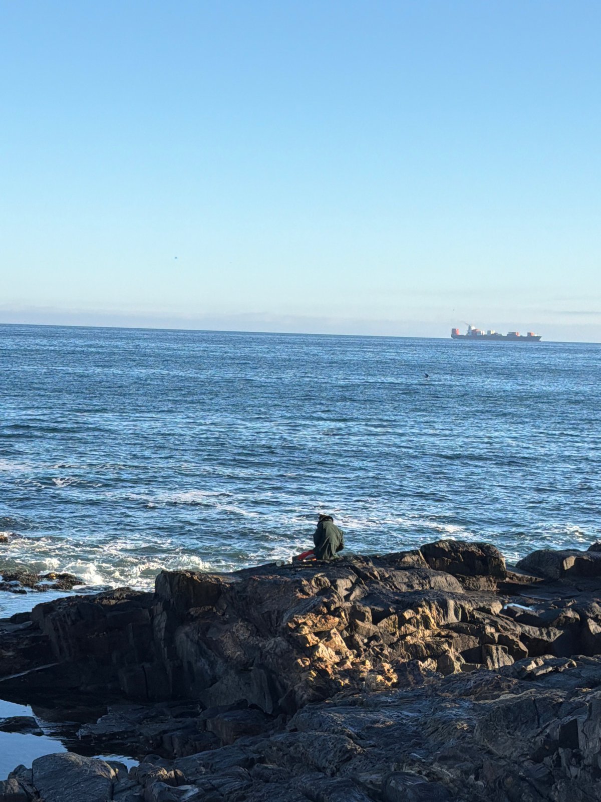 Person stands on Cape Town clifftop overlooking ocean Saturday morning