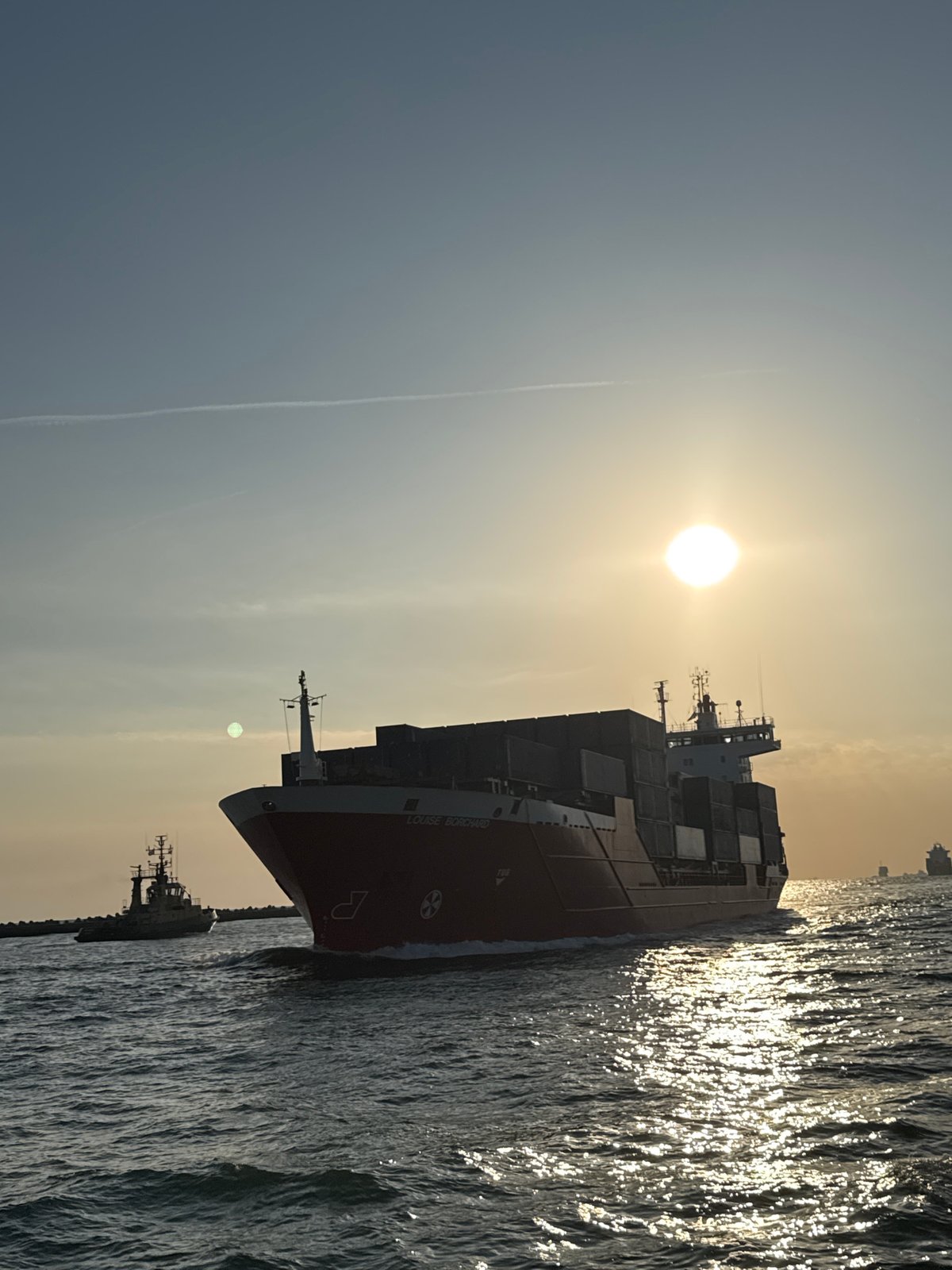 Cargo ship and sailboat share the Adriatic at sunrise near Ravenna