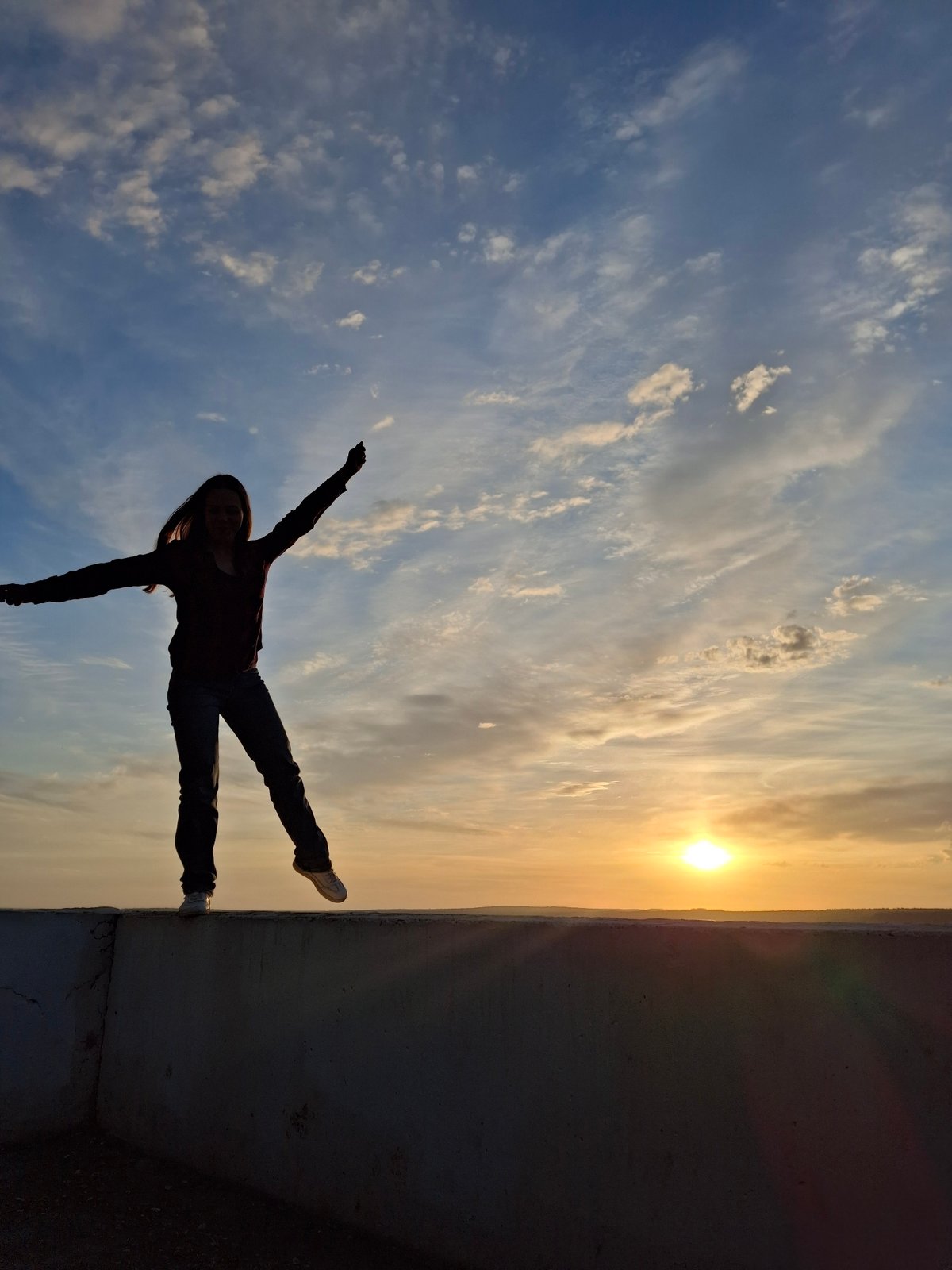 Person photographed balancing on ledge at sunset in Chaikovsky