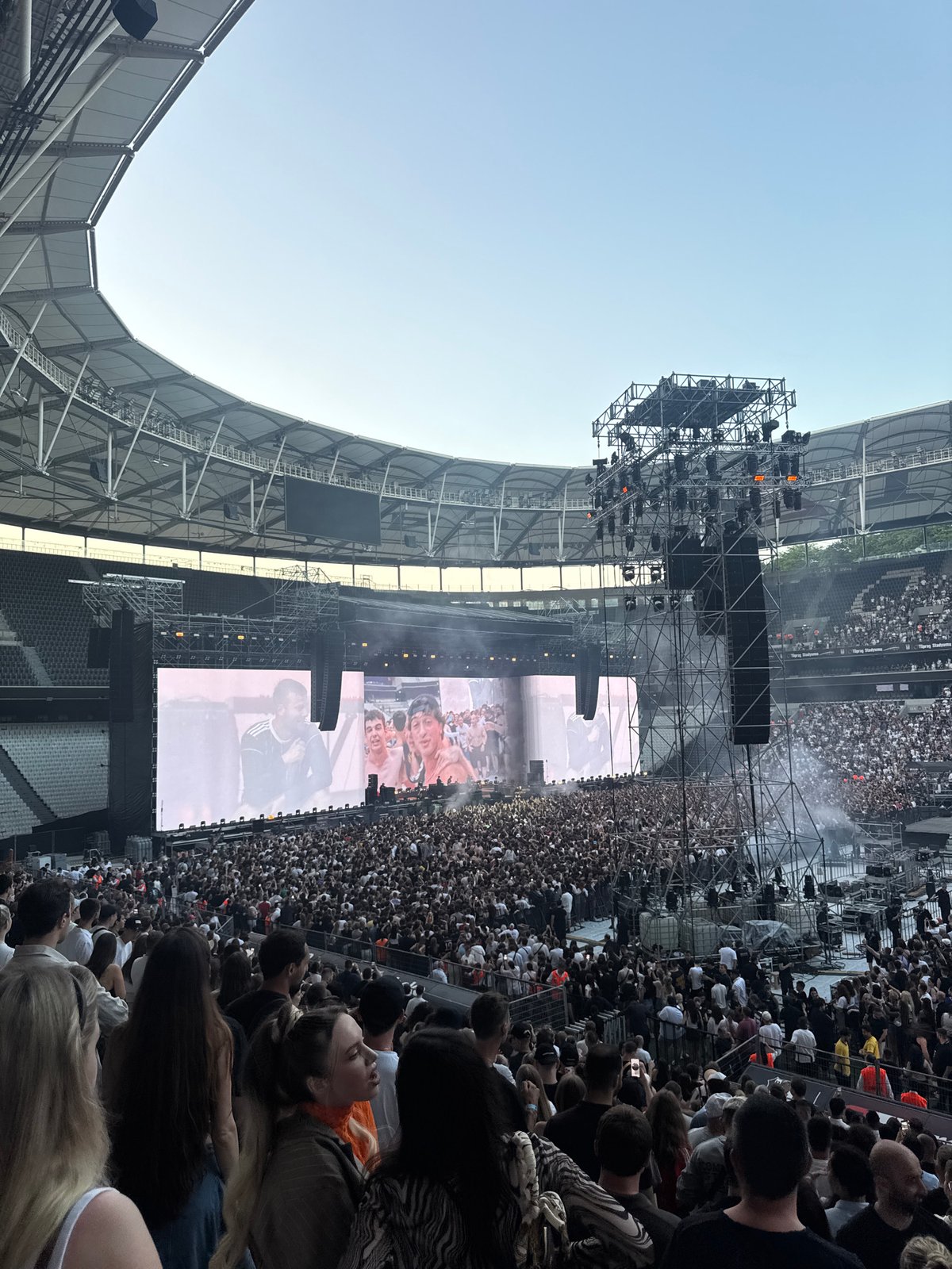 Outdoor concert observed at modern stadium under clear skies
