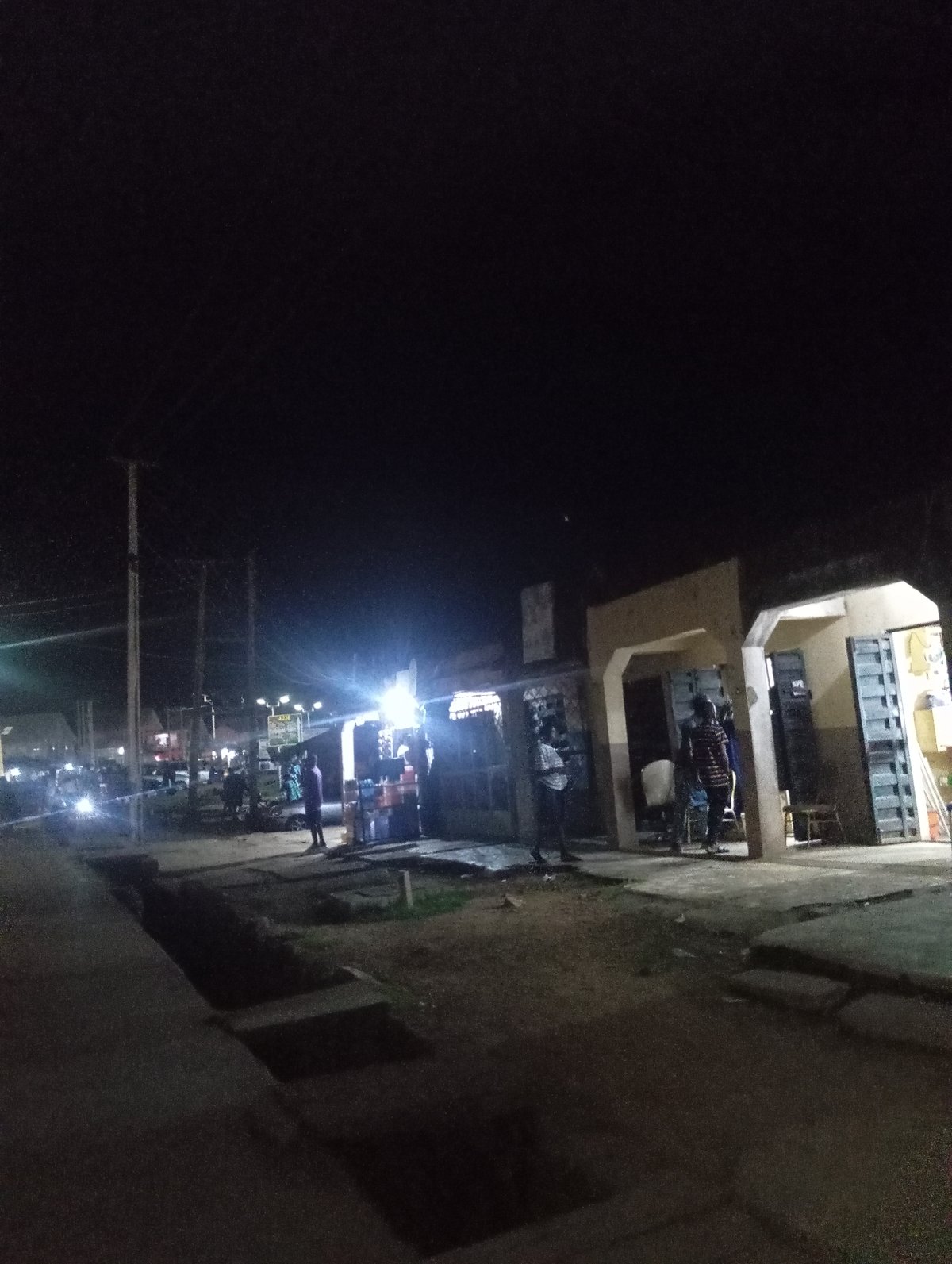 Nighttime urban street scene with vendors, signage, and foot traffic.