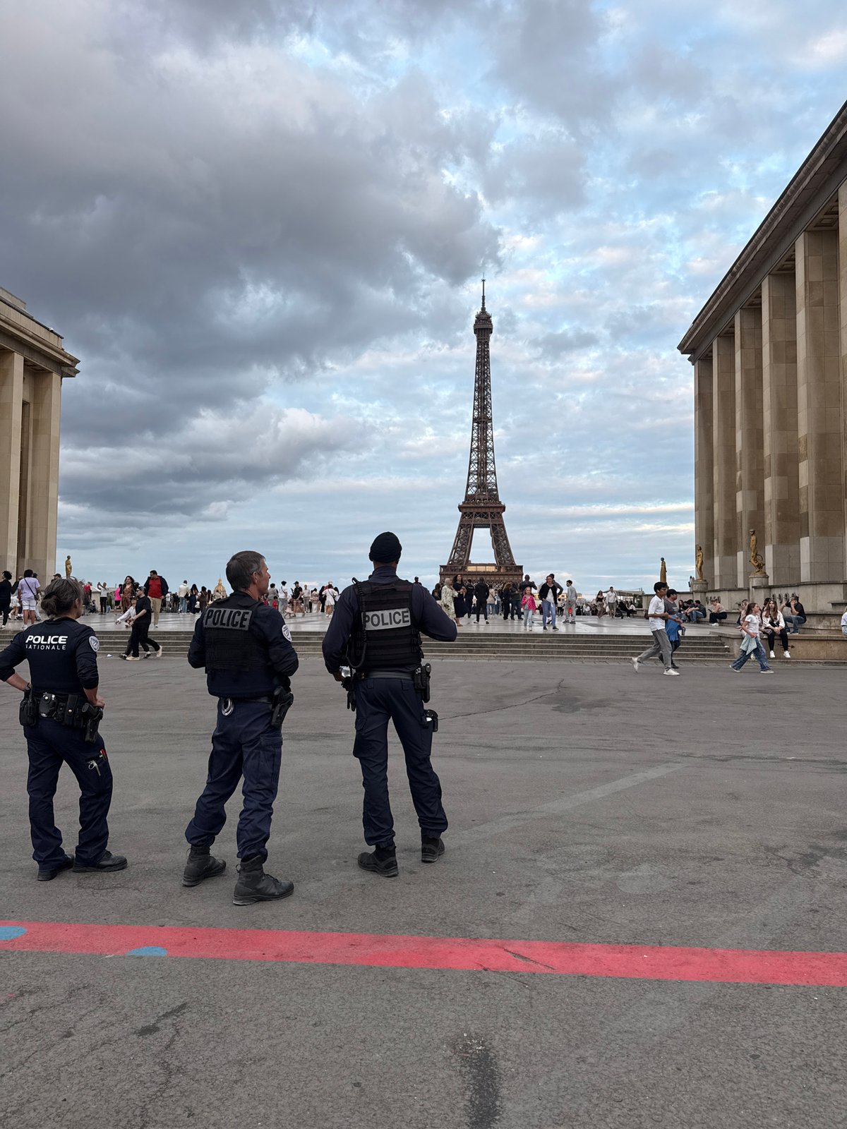 Evening crowds and police patrol near Eiffel Tower