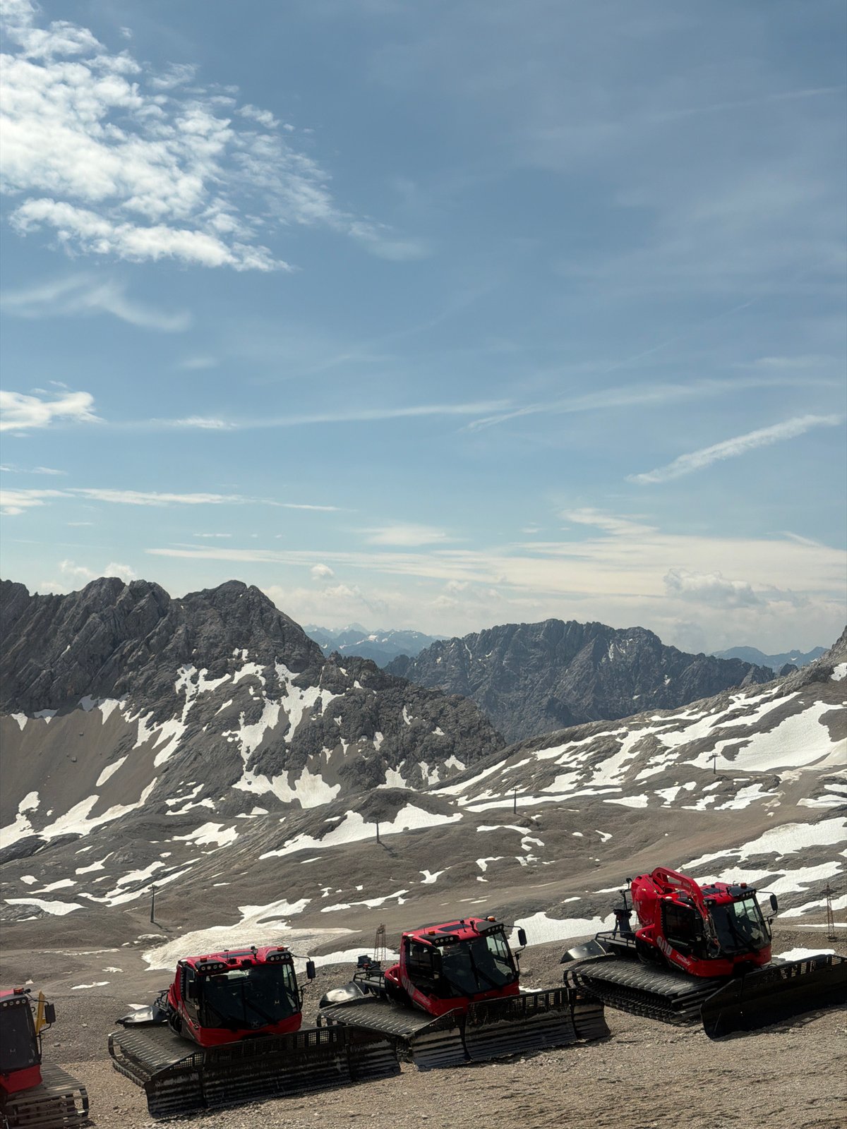Snow groomers parked on a rocky Alpine summit in summer