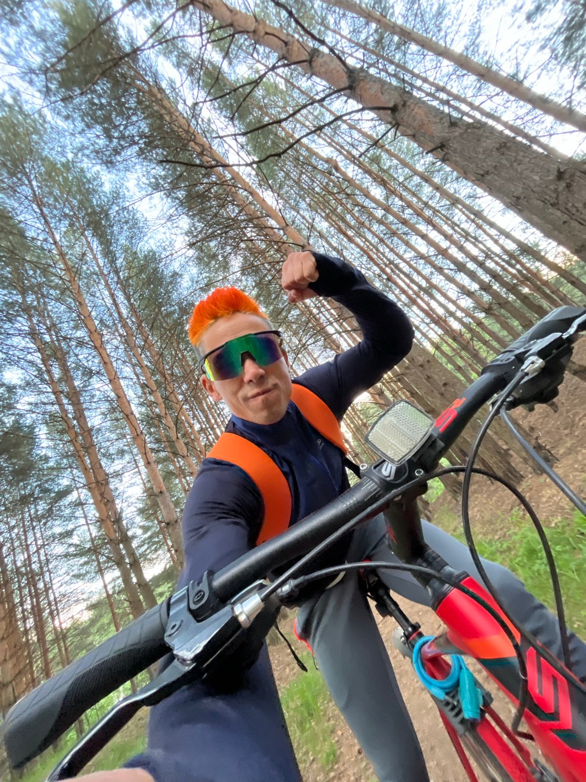 Orange-haired cyclist mountain bikes, poses for selfies near Kama River