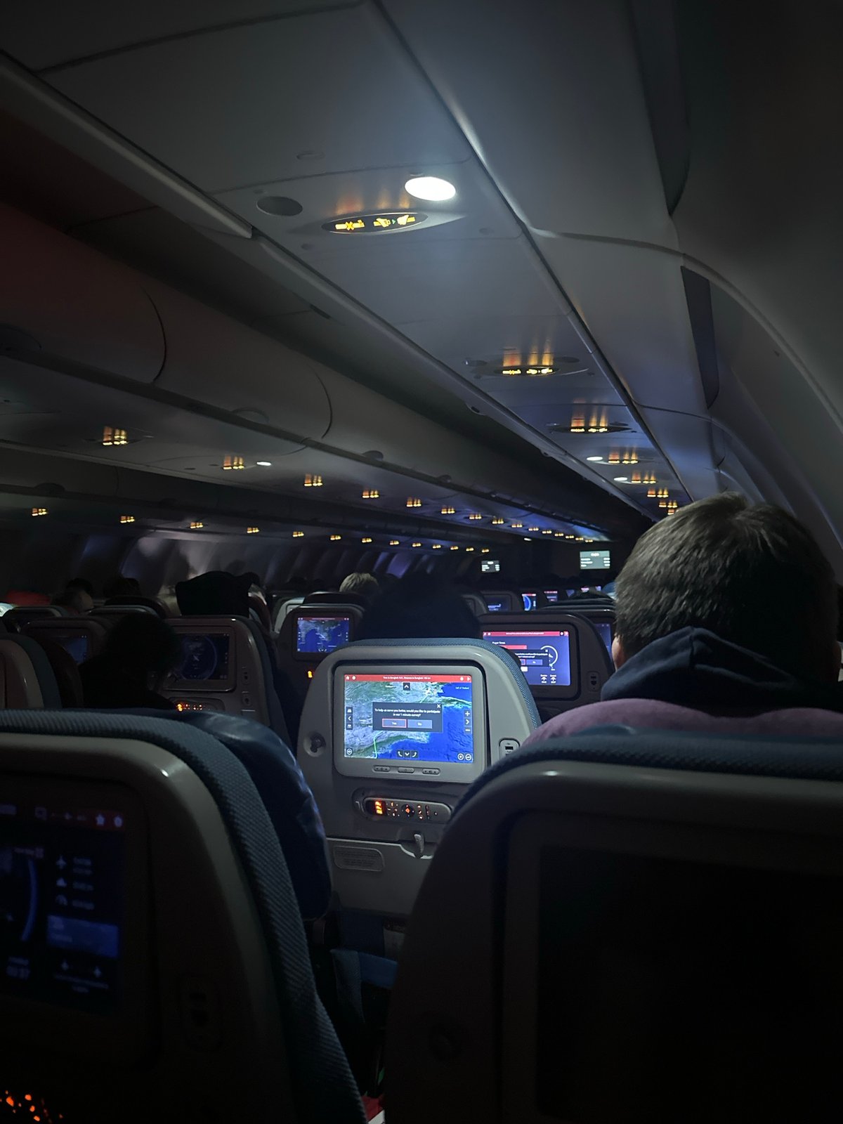 Nighttime flight cabin with seatbelt signs illuminated