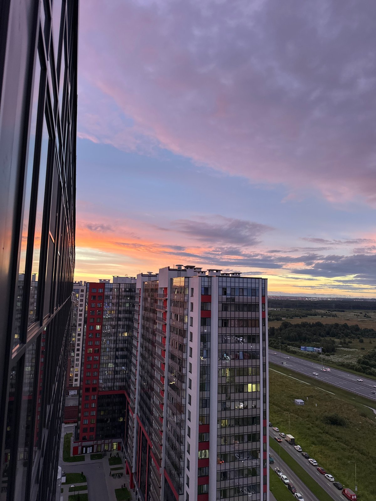 Sunset over St. Petersburg's outskirts — towers, forest, and highway