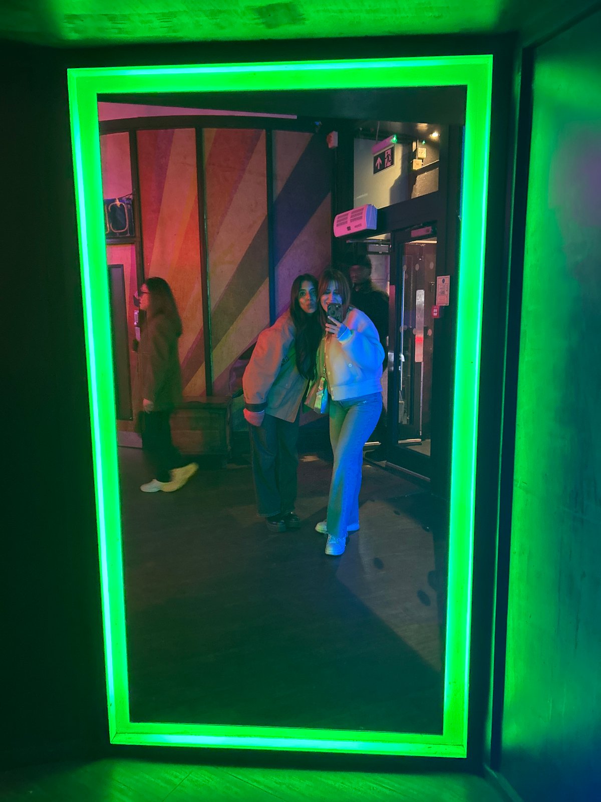 Green illuminated frame displays distorted building interior reflection in London