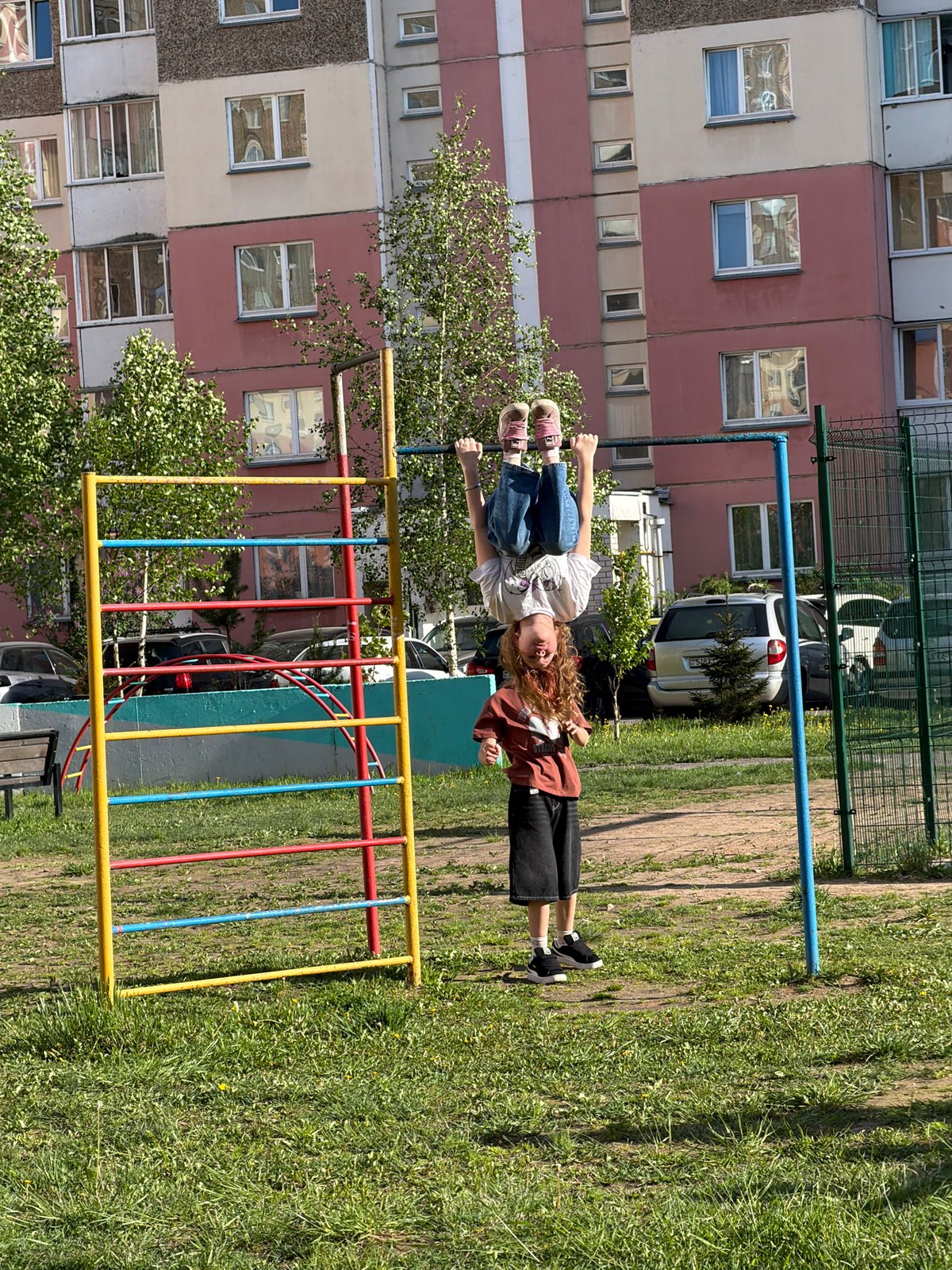 Two people hang upside down from urban monkey bars