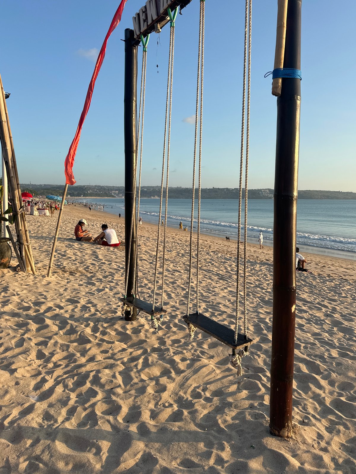 Kuta Beach at golden hour — swings, dining, and a calm sea
